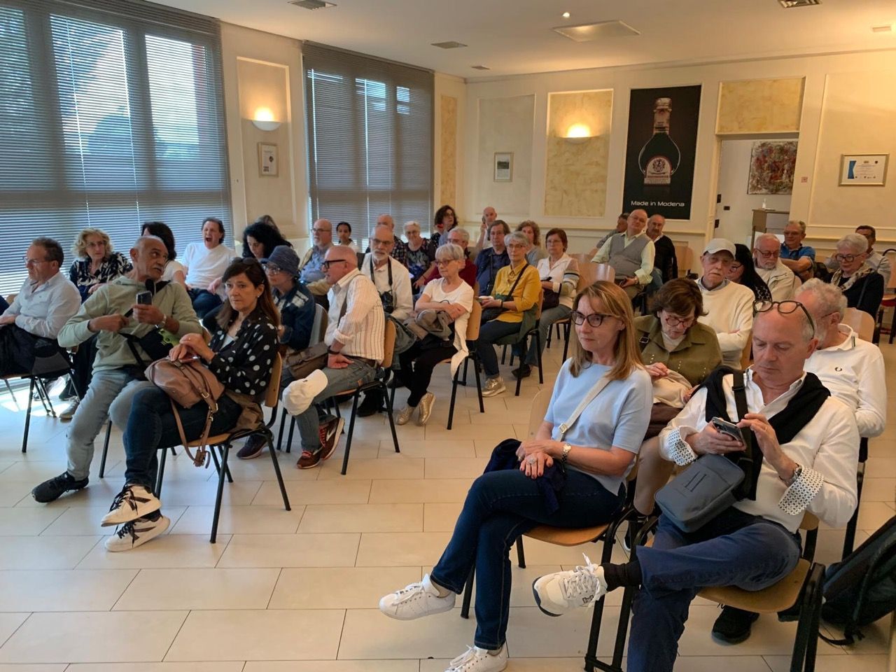 Un gruppo di persone è seduto su delle sedie in una stanza.