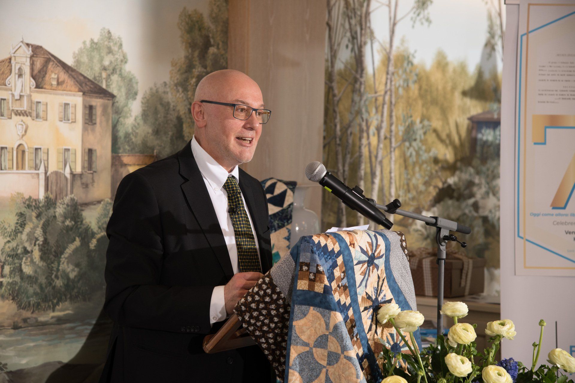 Un uomo in giacca e cravatta è in piedi su un podio e tiene un discorso.