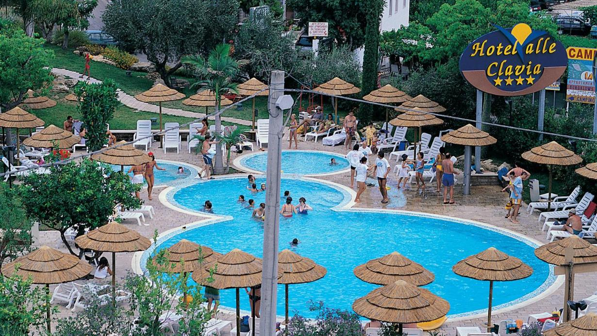 Una grande piscina circondata da ombrelloni e sdraio in paglia
