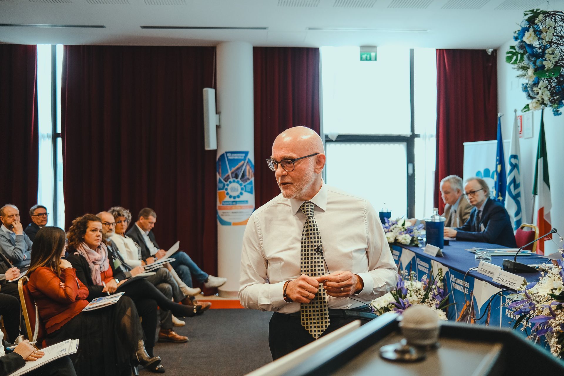 Un uomo è in piedi su un podio e fa una presentazione a un gruppo di persone.