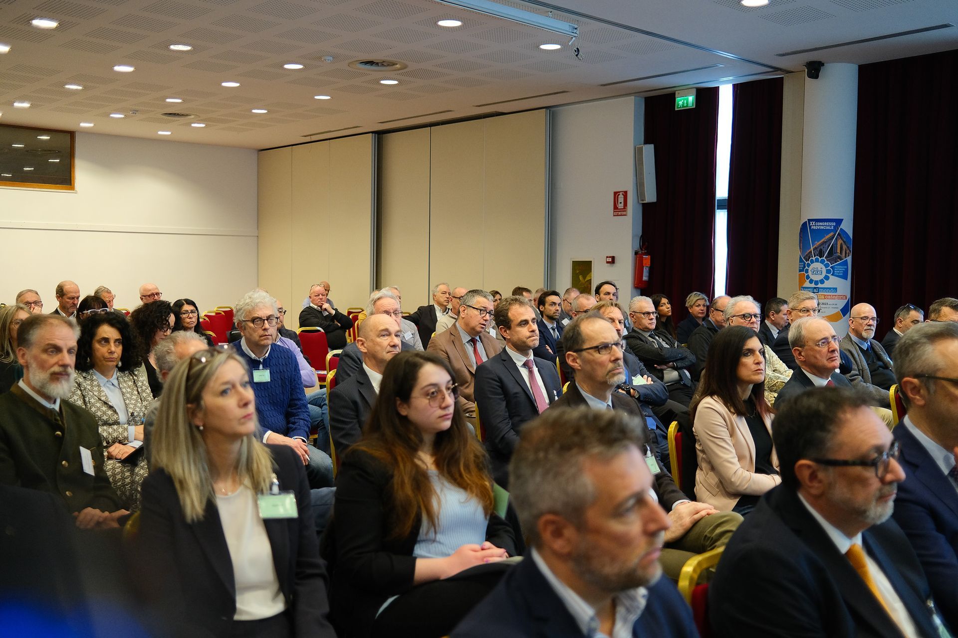 Un folto gruppo di persone è seduto in una stanza e guarda una presentazione.