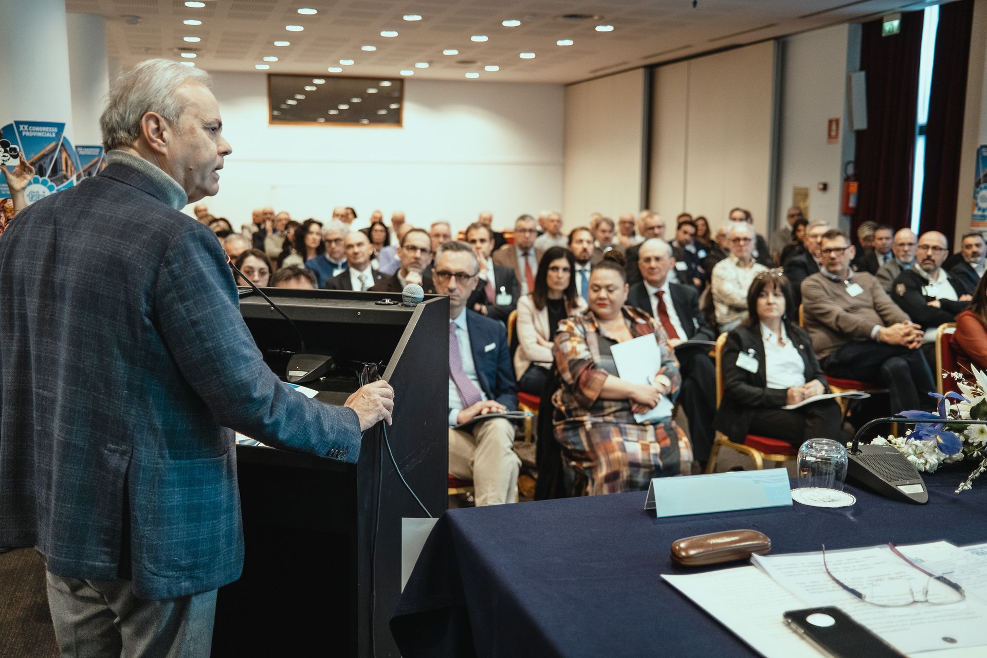 Un uomo sta facendo una presentazione a un folto gruppo di persone in una sala conferenze.