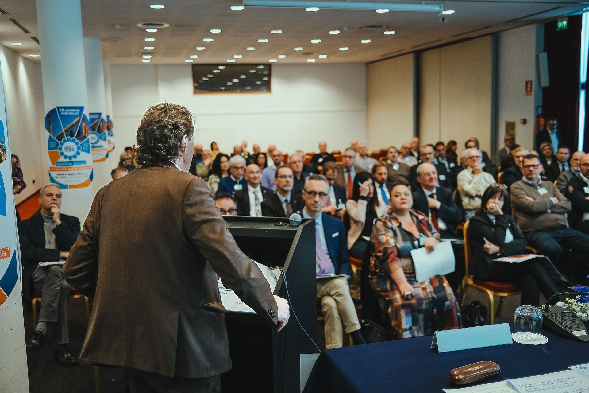 Un uomo sta facendo una presentazione a un folto gruppo di persone in una sala conferenze.