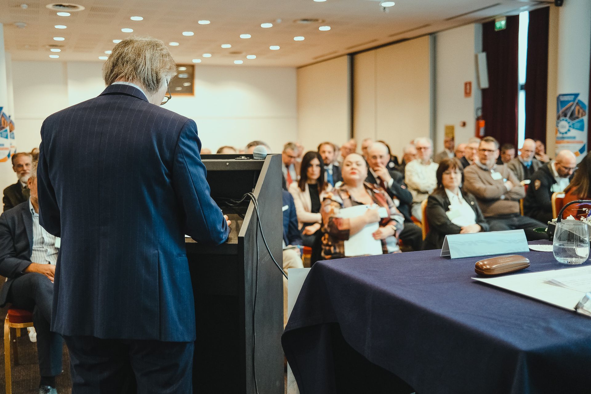 Un uomo in giacca e cravatta è in piedi su un podio di fronte a una folla di persone.