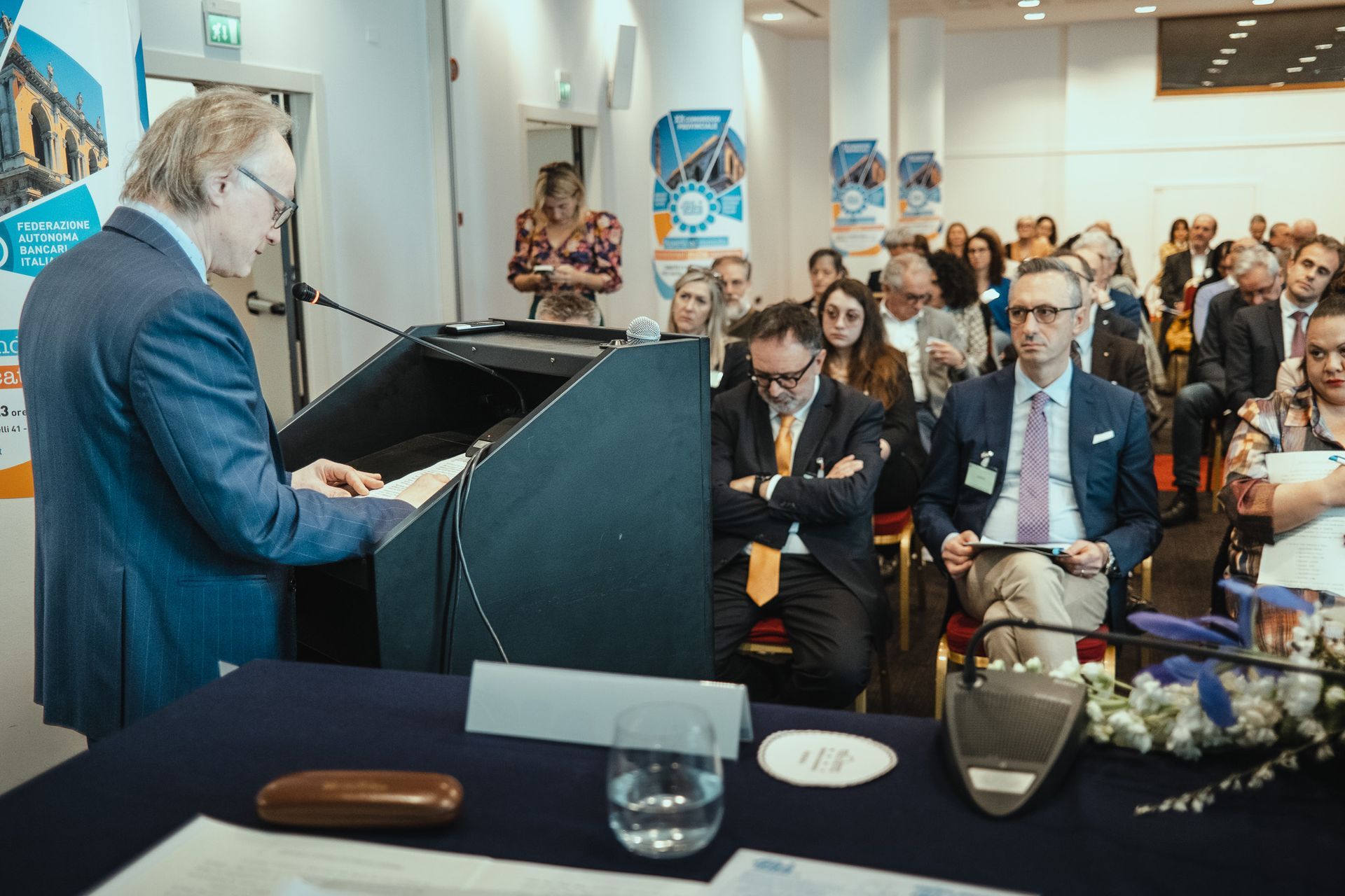 Un uomo tiene un discorso su un podio davanti a una folla di persone.