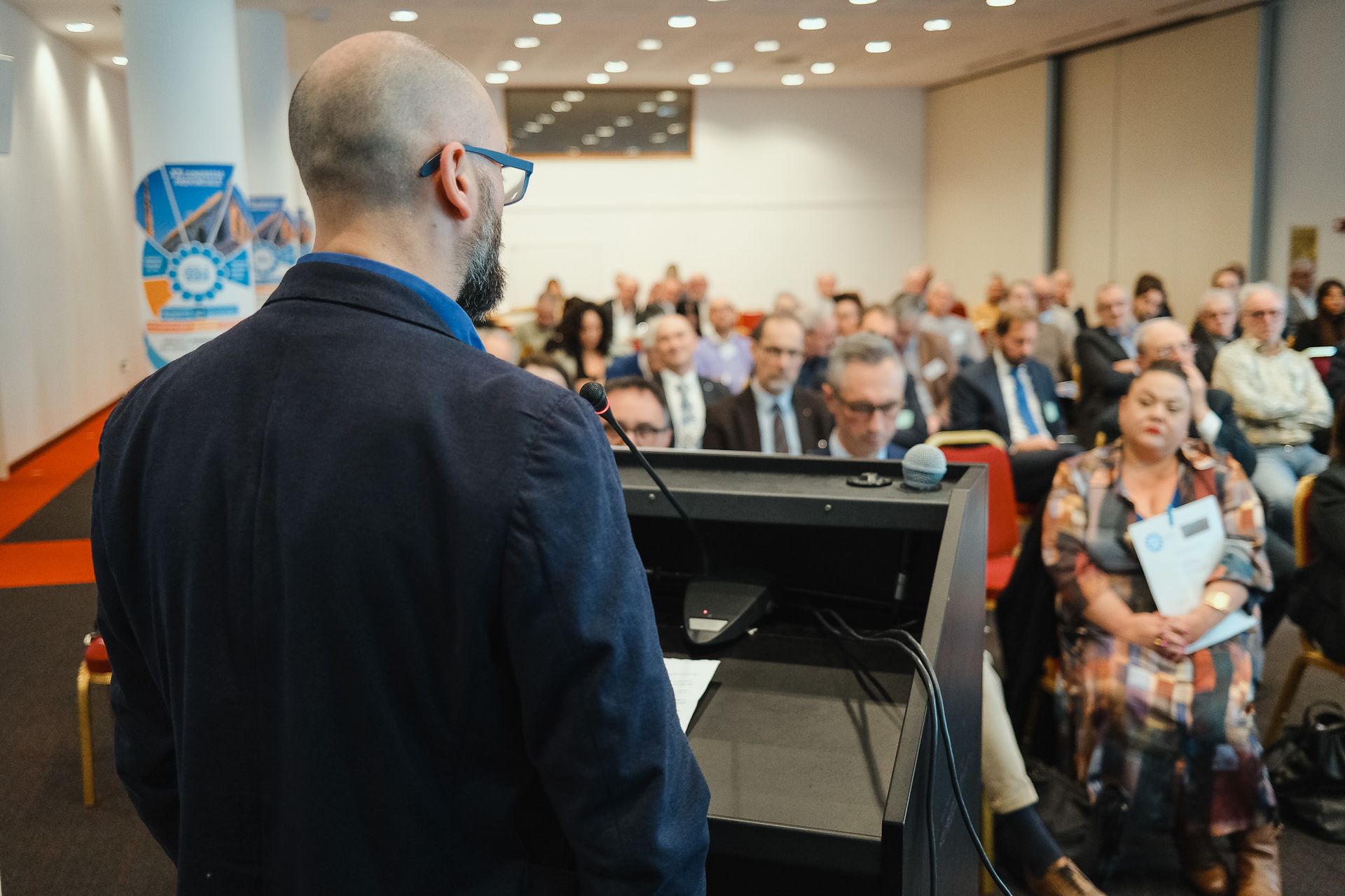 Un uomo tiene un discorso davanti a una folla di persone in una sala conferenze.