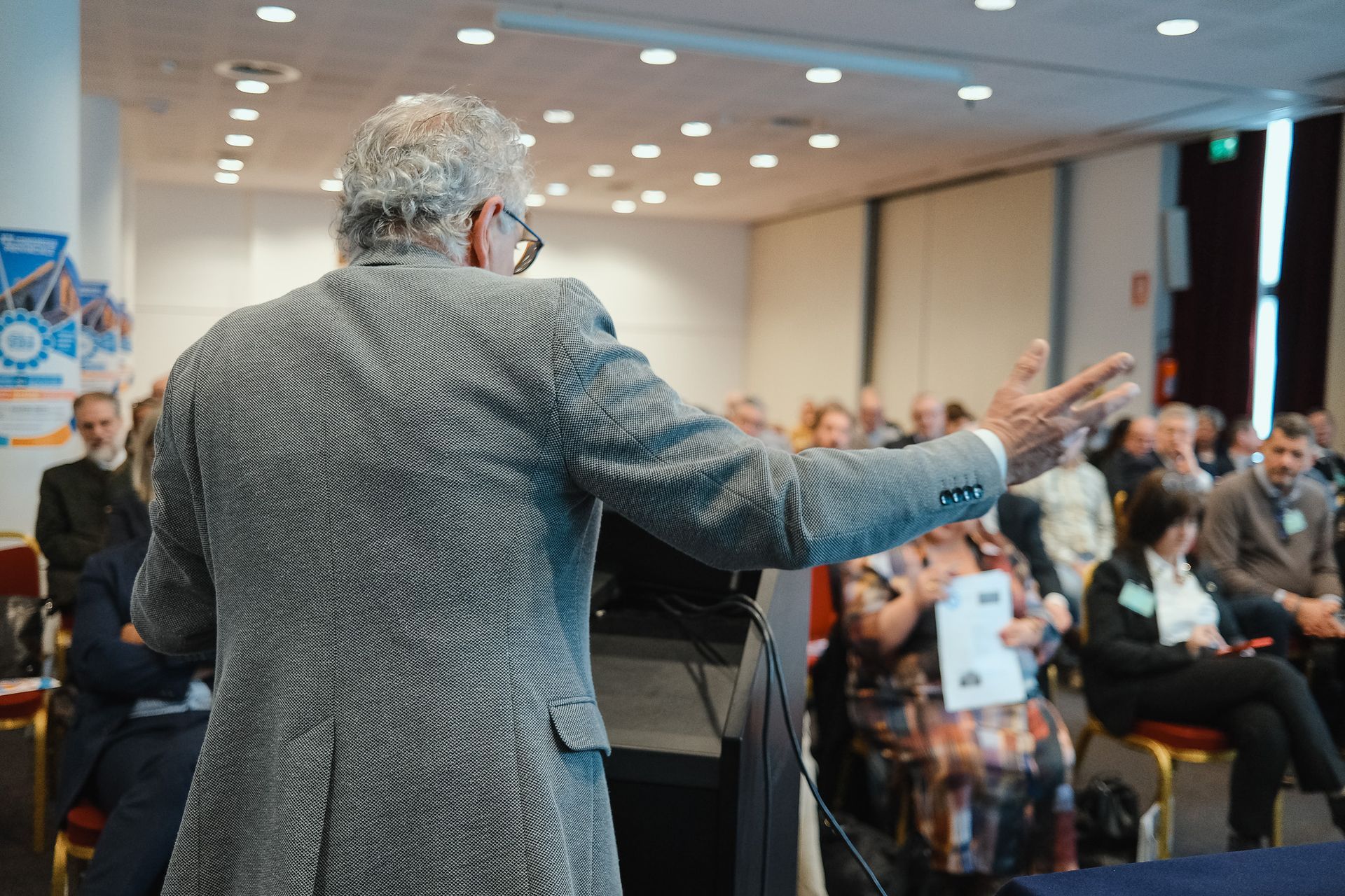 Un uomo tiene un discorso davanti a una folla di persone in una sala conferenze.