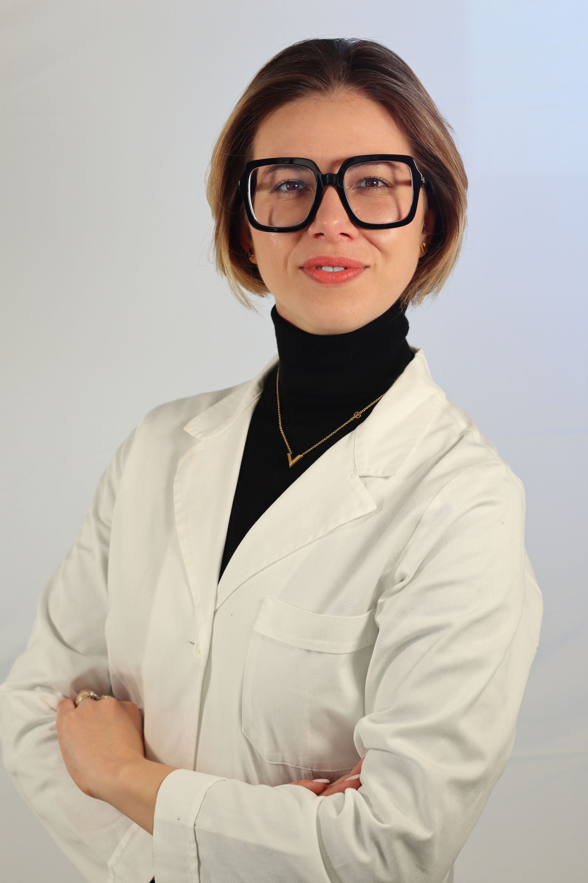 Una donna che indossa occhiali e camice bianco posa per una foto.