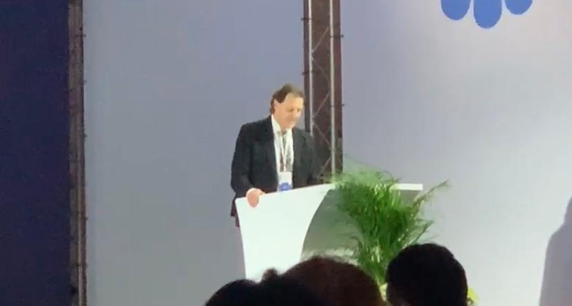 Un uomo in giacca e cravatta è in piedi su un podio e tiene un discorso.