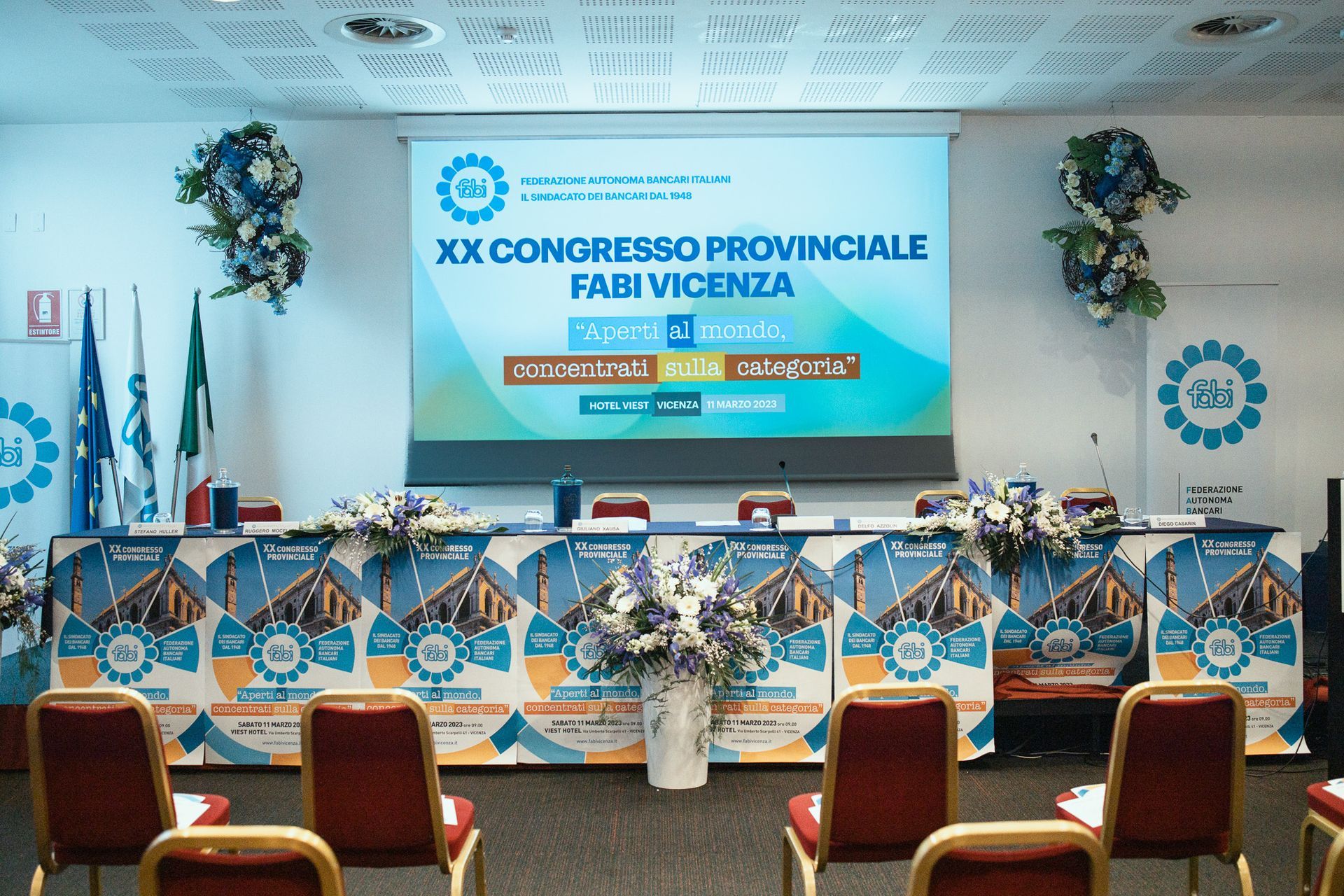 Una sala conferenze con uno schermo per proiettori con scritto xx congresso provinciale