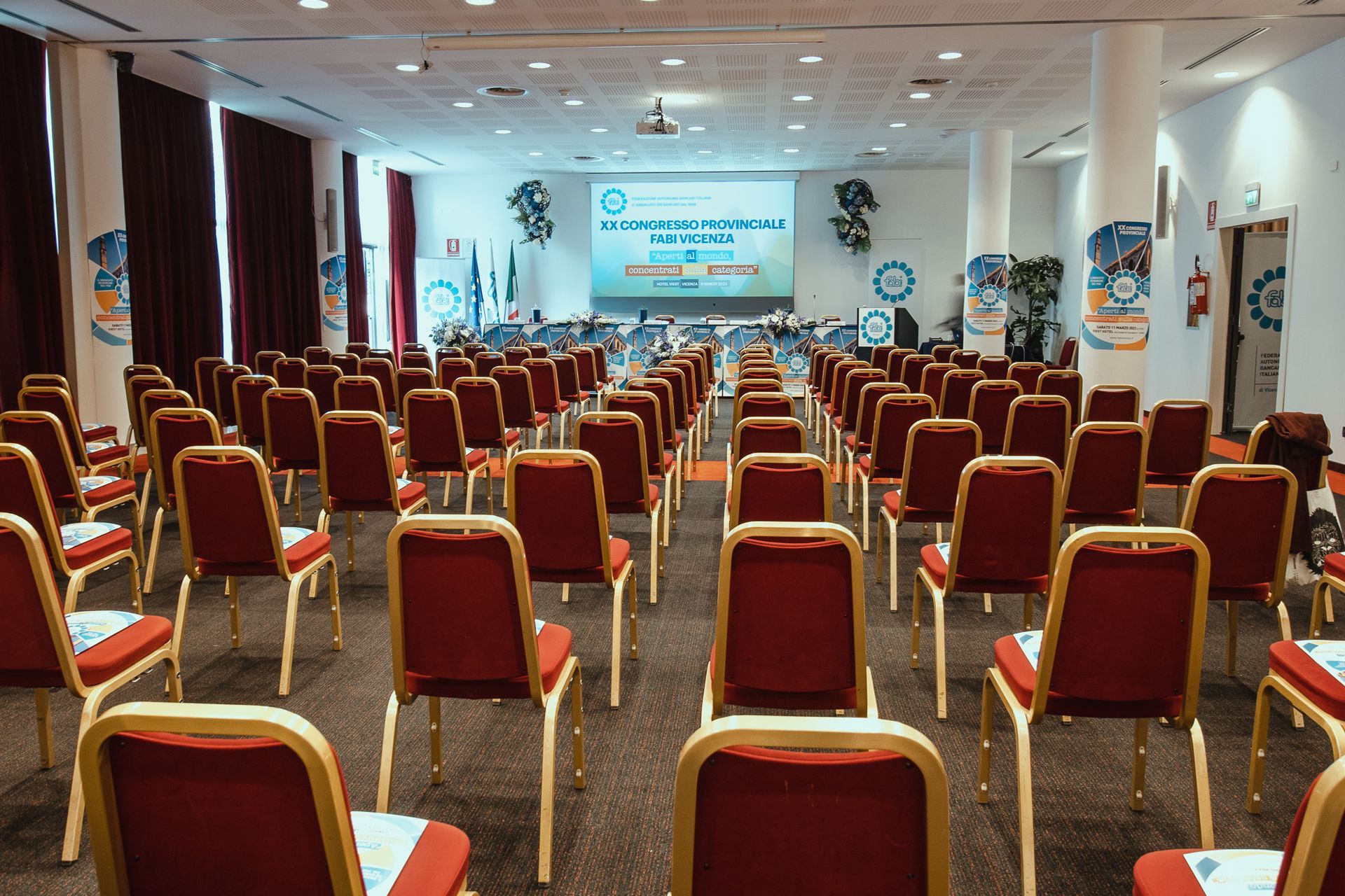 File di sedie rosse sono allineate in una sala conferenze