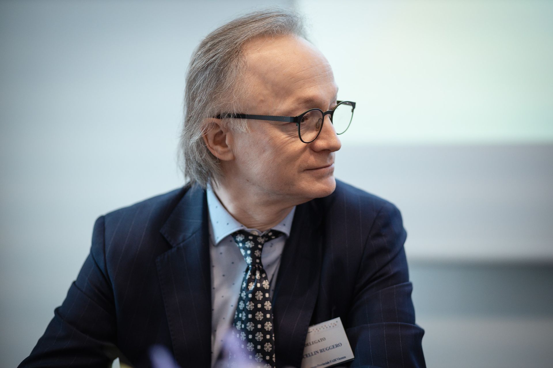 Un uomo in giacca e cravatta è seduto a un tavolo.