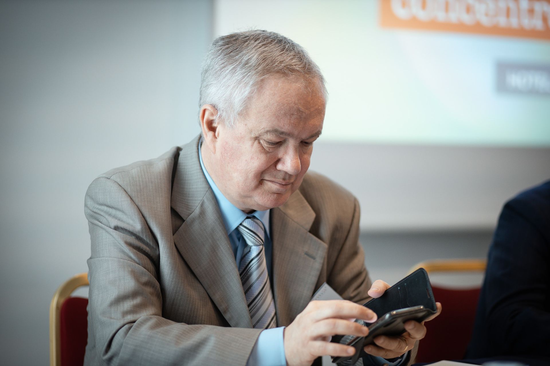 Un uomo in giacca e cravatta guarda il suo cellulare.