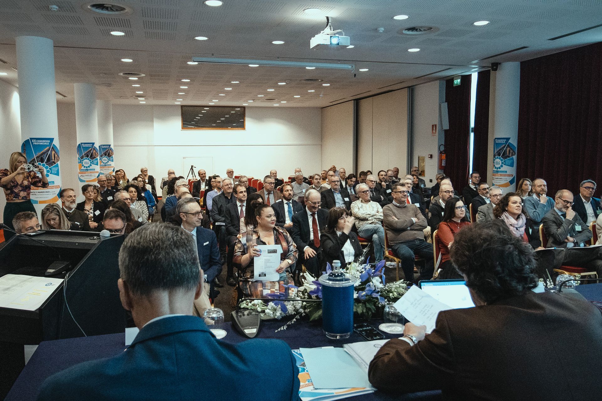 Un folto gruppo di persone è seduto in una sala conferenze