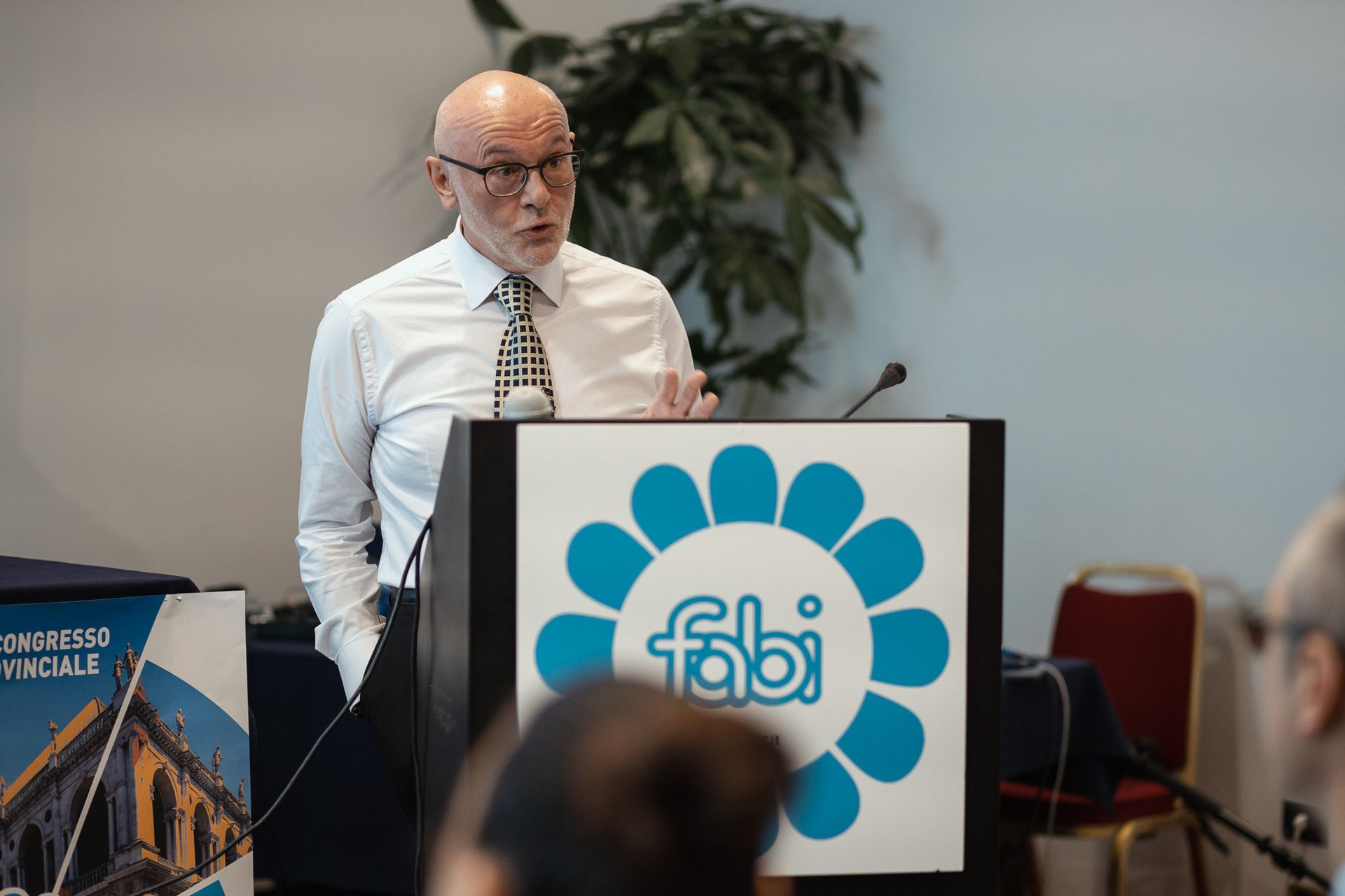 Un uomo tiene un discorso su un podio con sopra il logo Fabi.