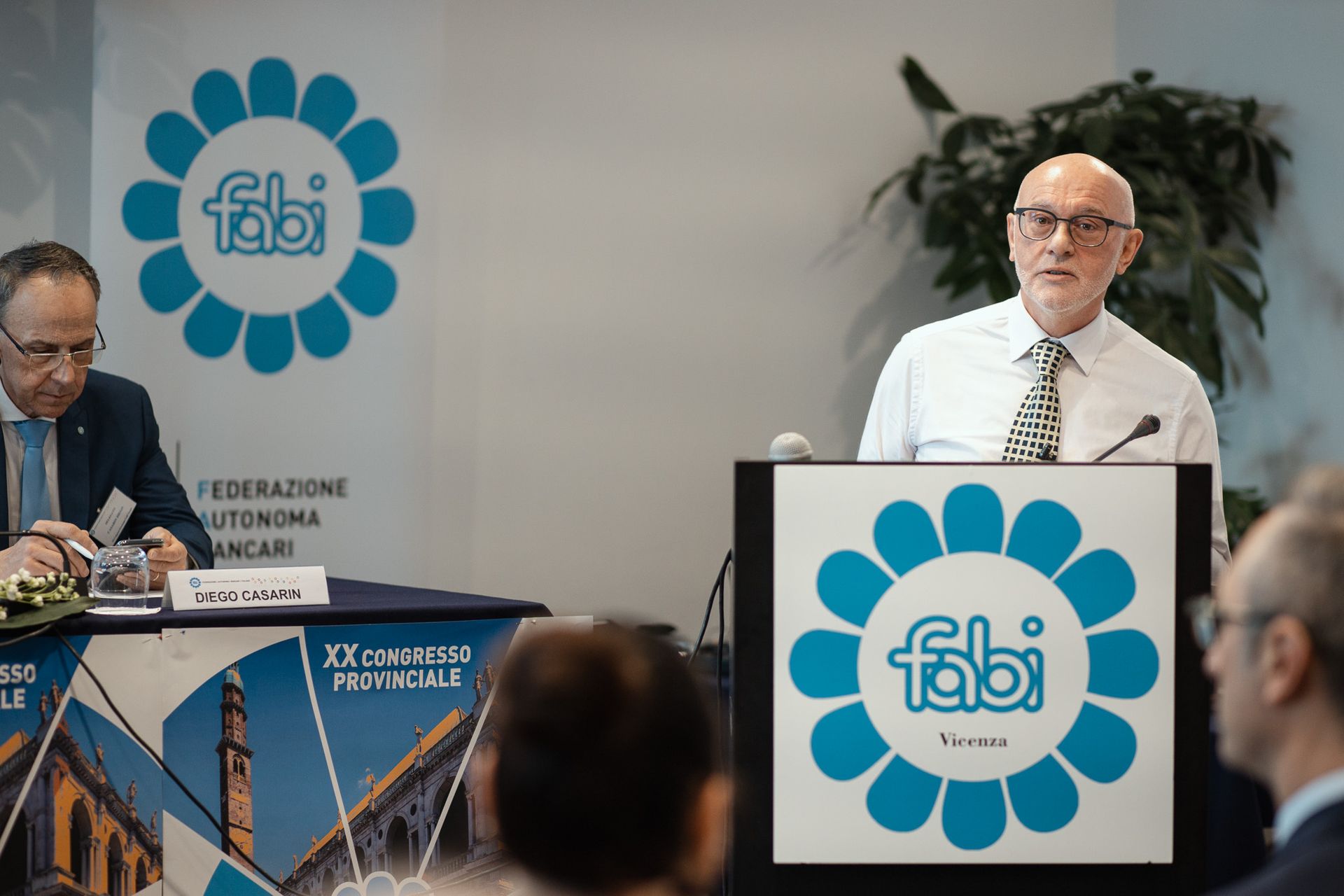 Un uomo tiene un discorso su un podio con sopra il logo Fabi.