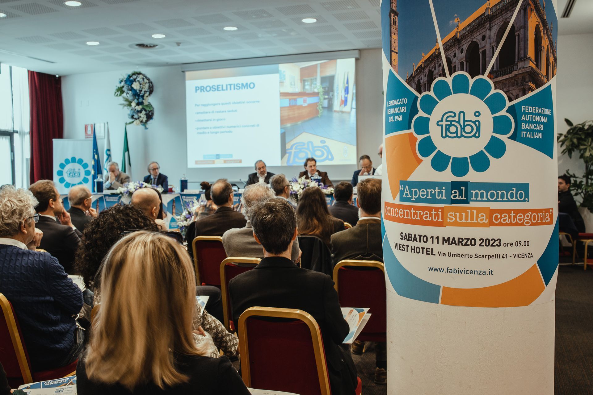 Un gruppo di persone è seduto in una stanza e guarda una presentazione.