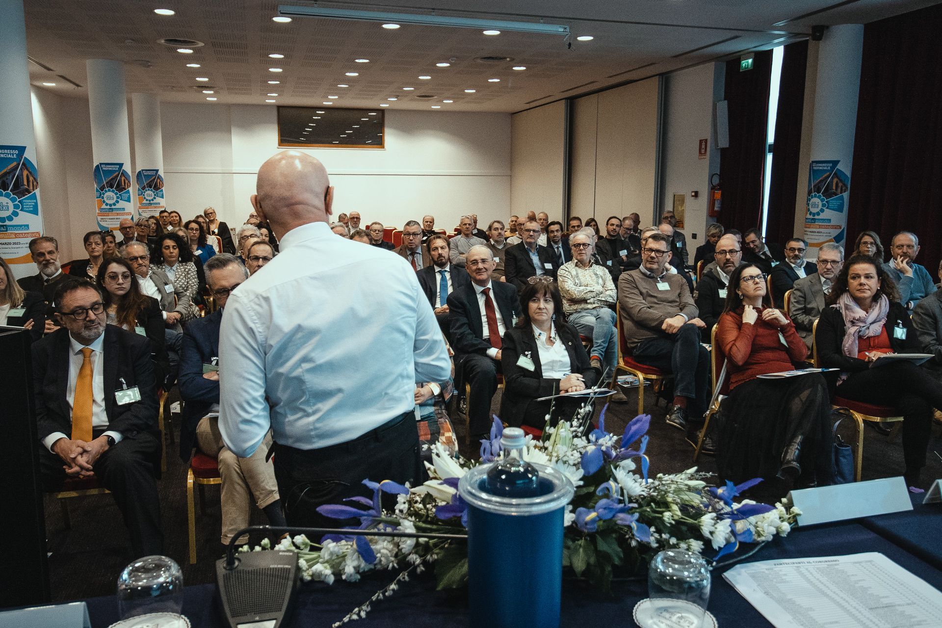Un uomo sta facendo una presentazione a un folto gruppo di persone in una sala conferenze.