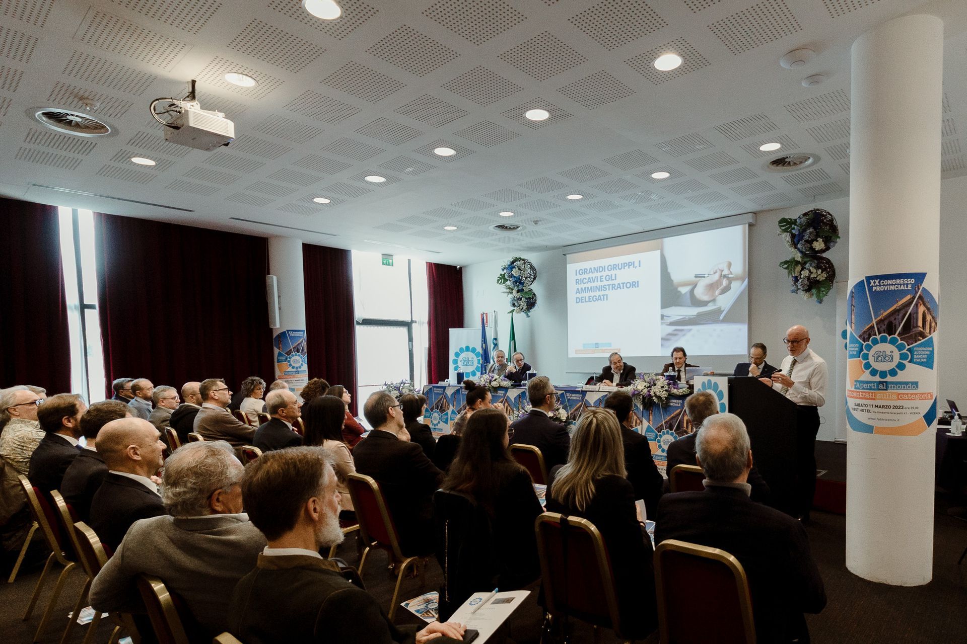 Un gruppo di persone è seduto in una sala conferenze e guarda una presentazione.