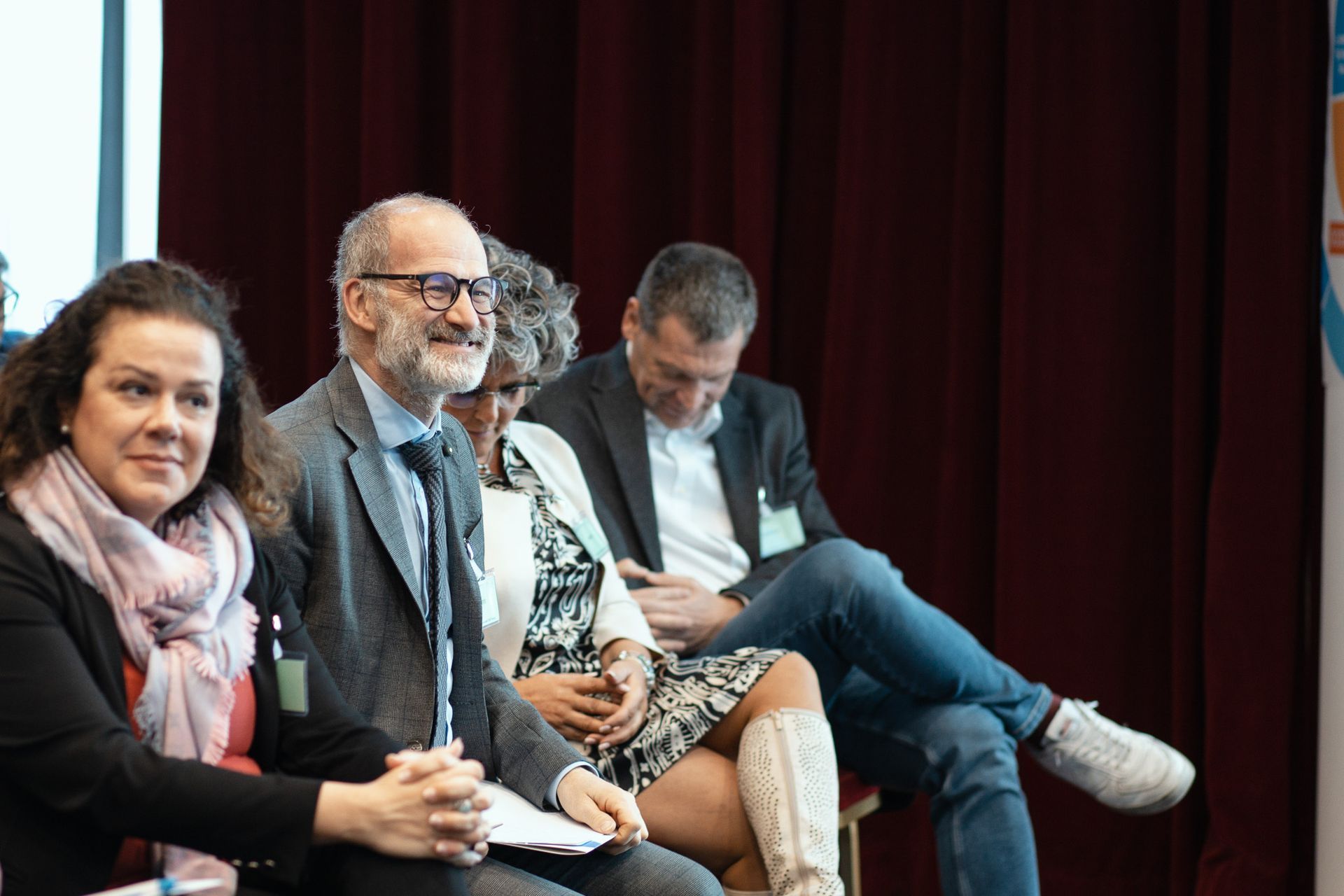 Un gruppo di persone è seduto in fila davanti a un microfono.