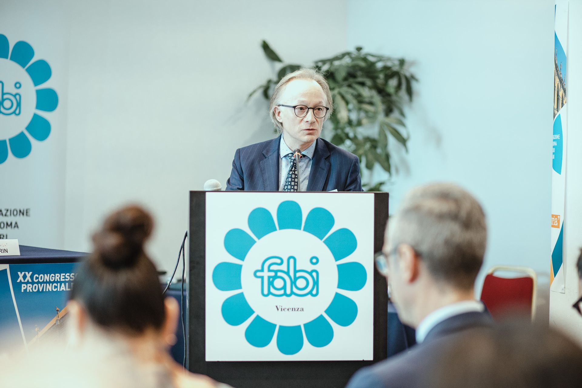 Un uomo tiene un discorso su un podio con sopra il logo Fabi.