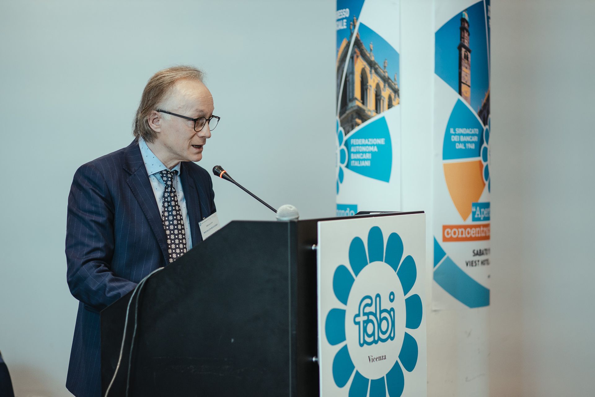 Un uomo in giacca e cravatta è in piedi su un podio e tiene un discorso.