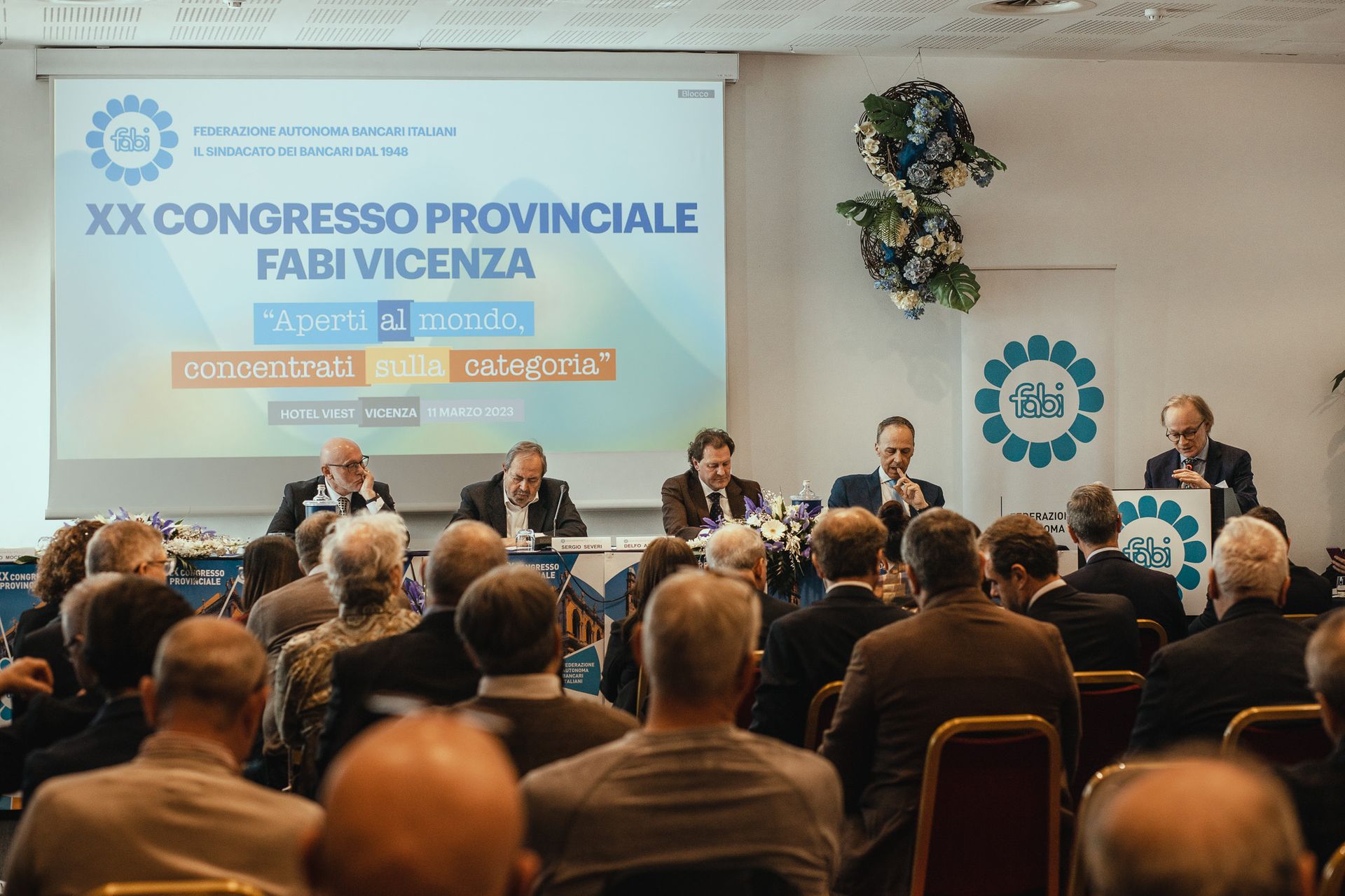 Un gruppo di persone è seduto in una stanza e guarda una presentazione.