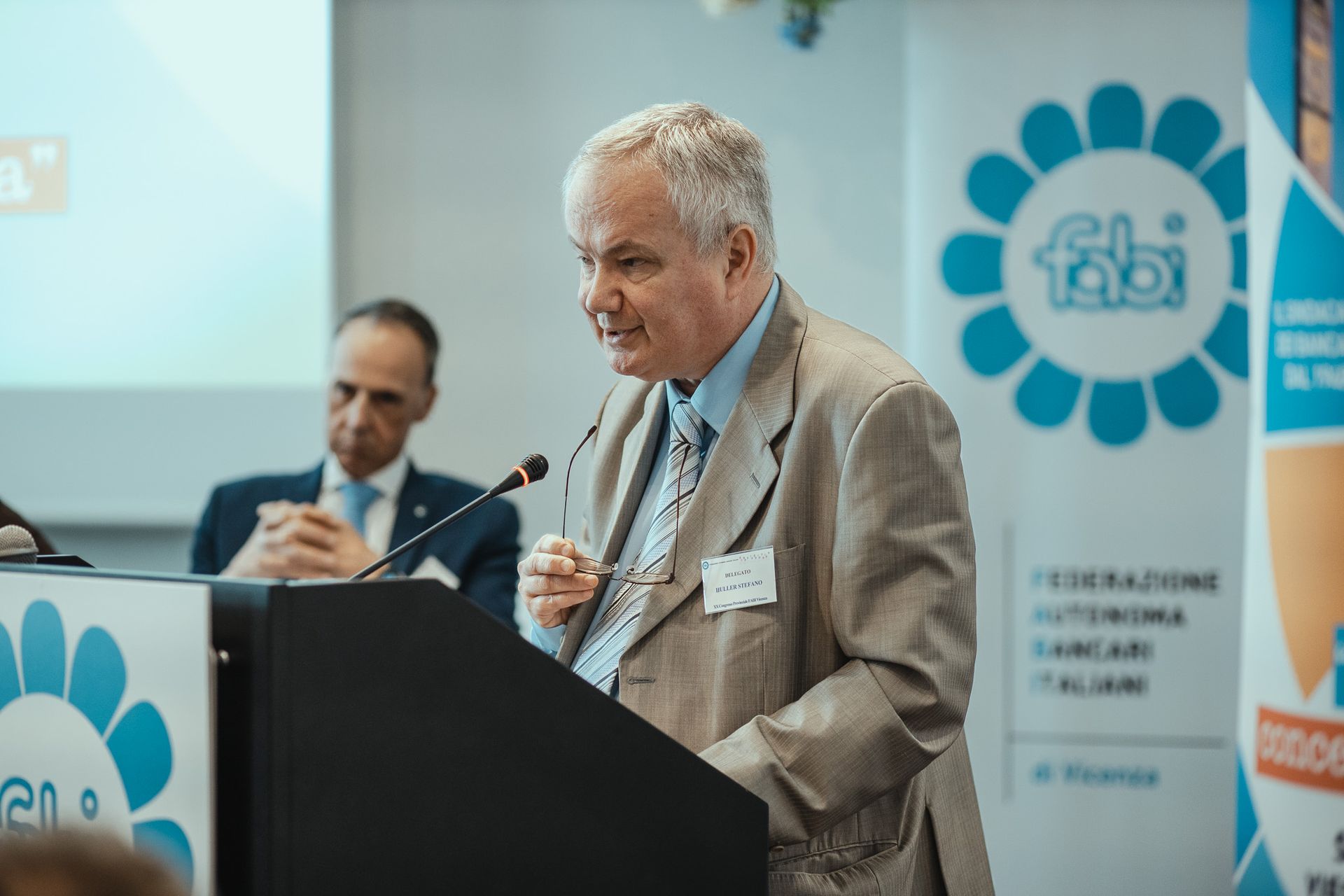 Un uomo in giacca e cravatta è in piedi su un podio e tiene un discorso.