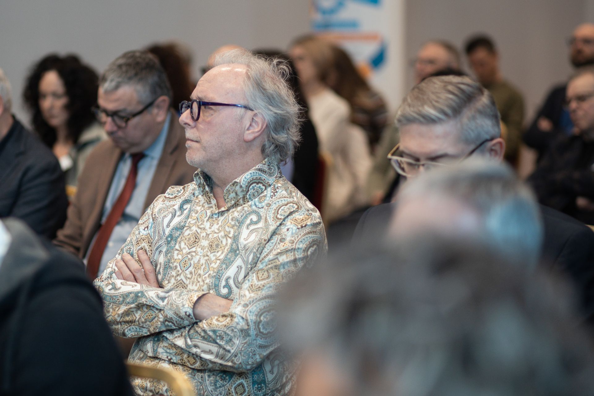 Un gruppo di persone è seduto in una stanza con le braccia incrociate.