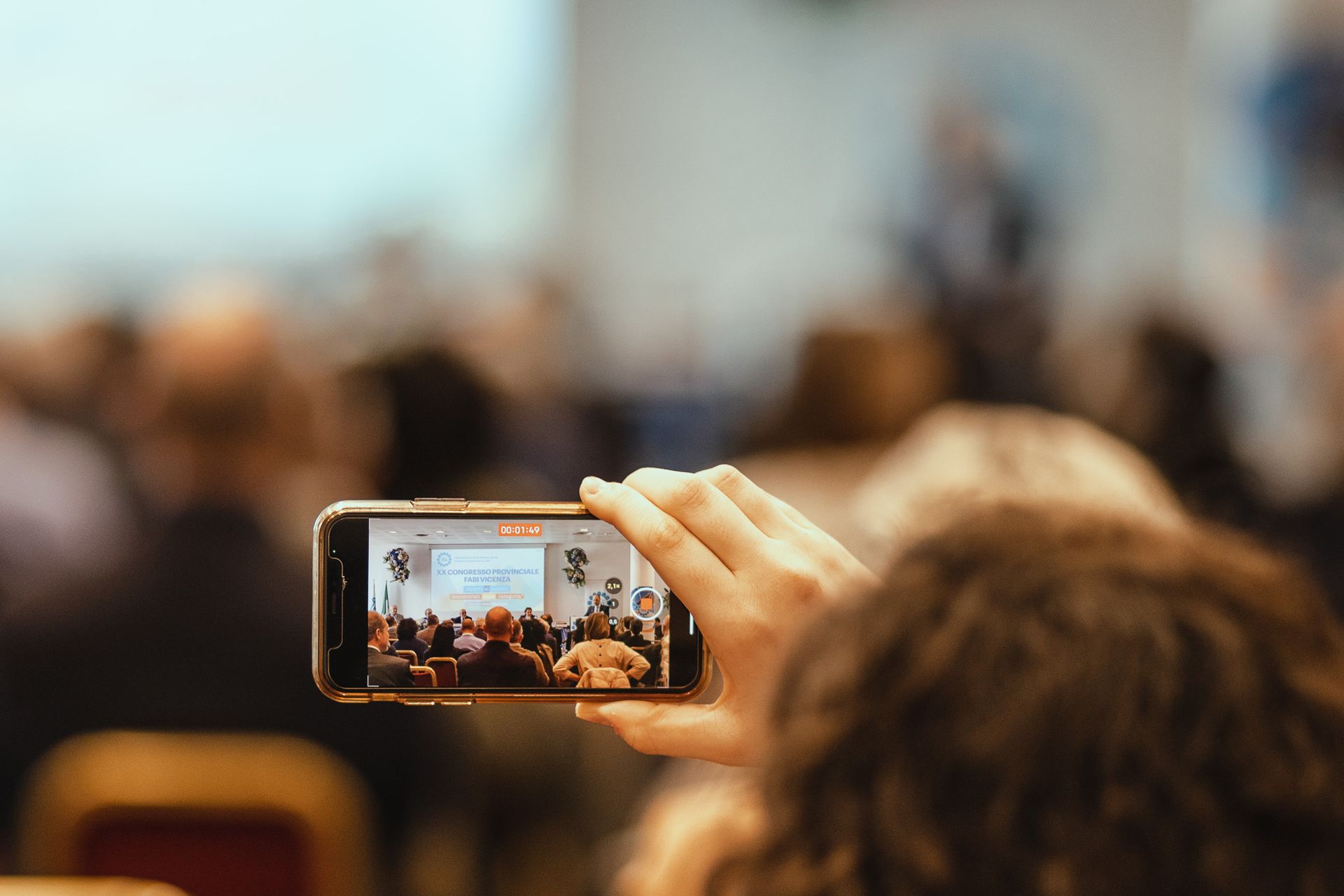Una persona sta scattando una foto di una folla con un cellulare.