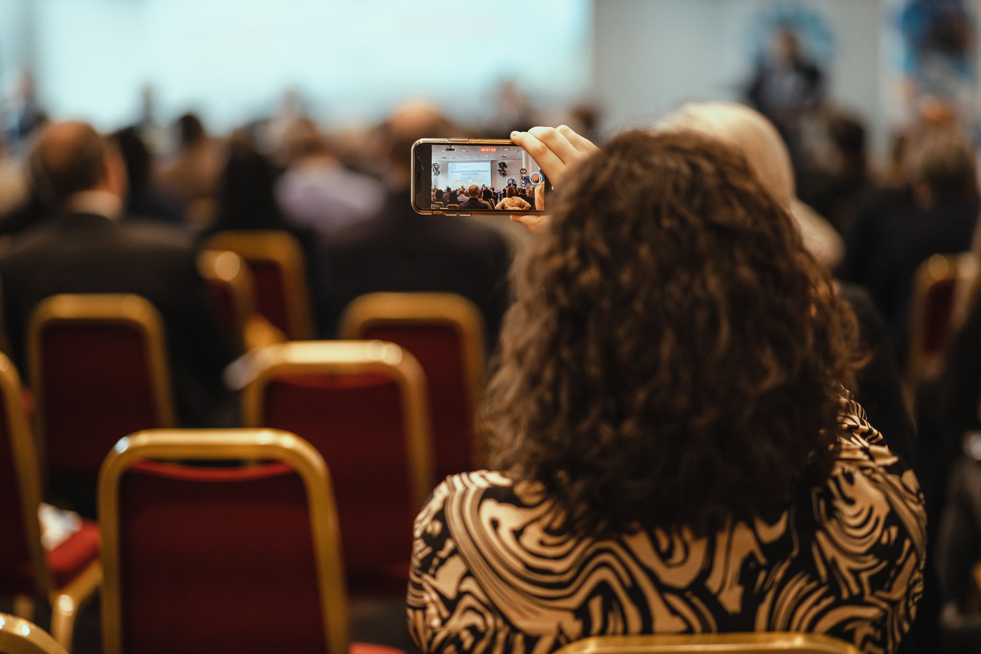 Una donna scatta una foto della folla con il cellulare.