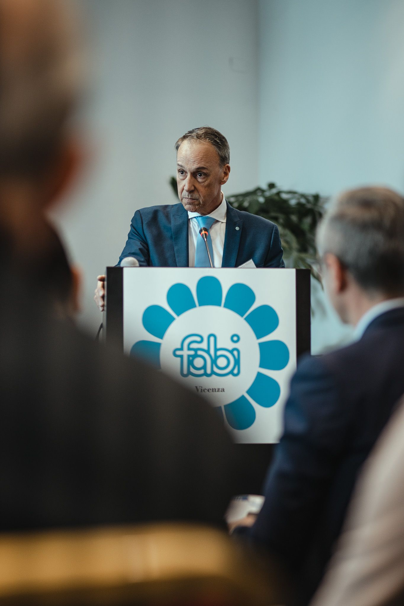 Un uomo in giacca e cravatta tiene un discorso su un podio.