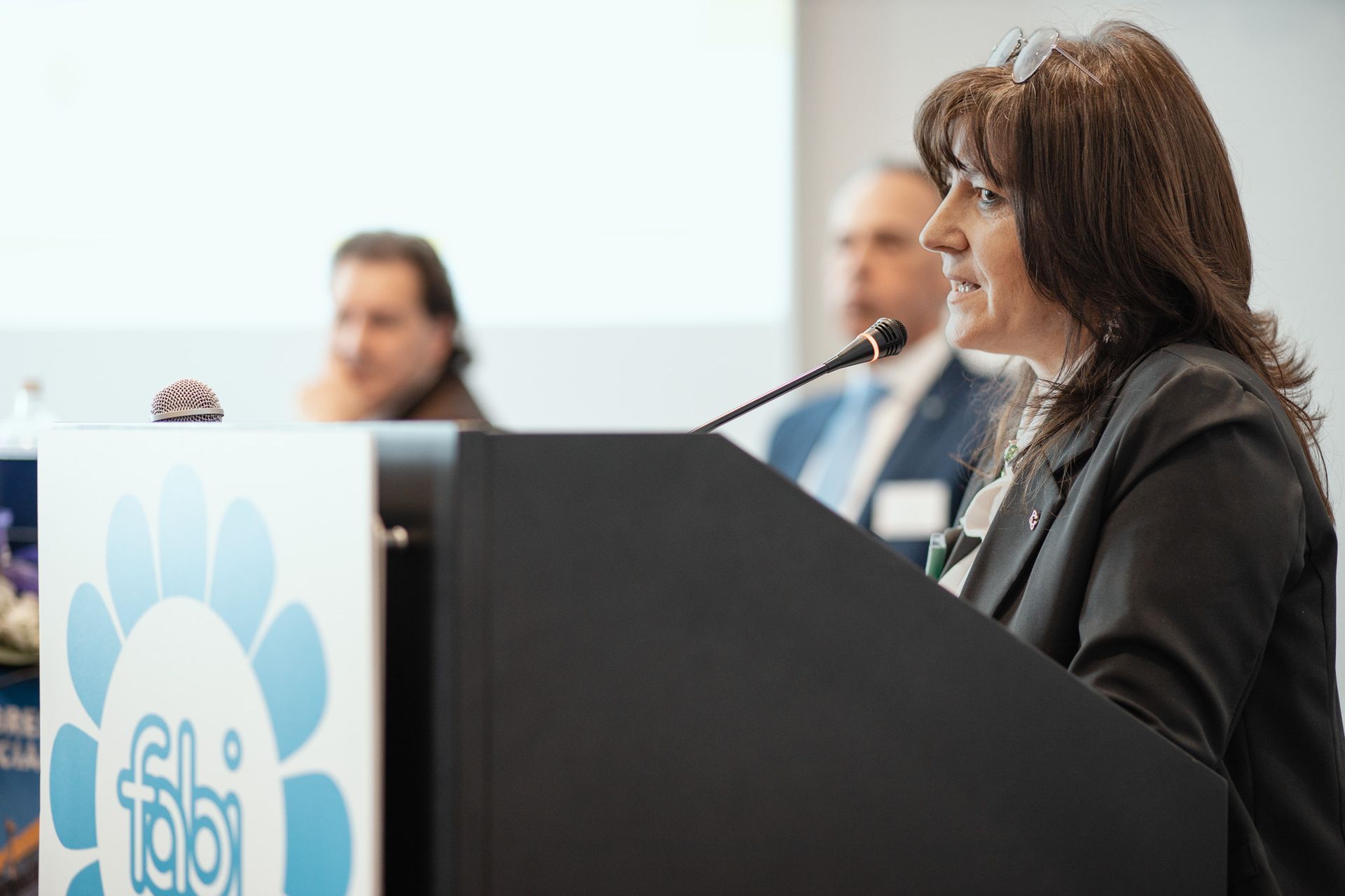 Una donna è in piedi su un podio e parla al microfono.