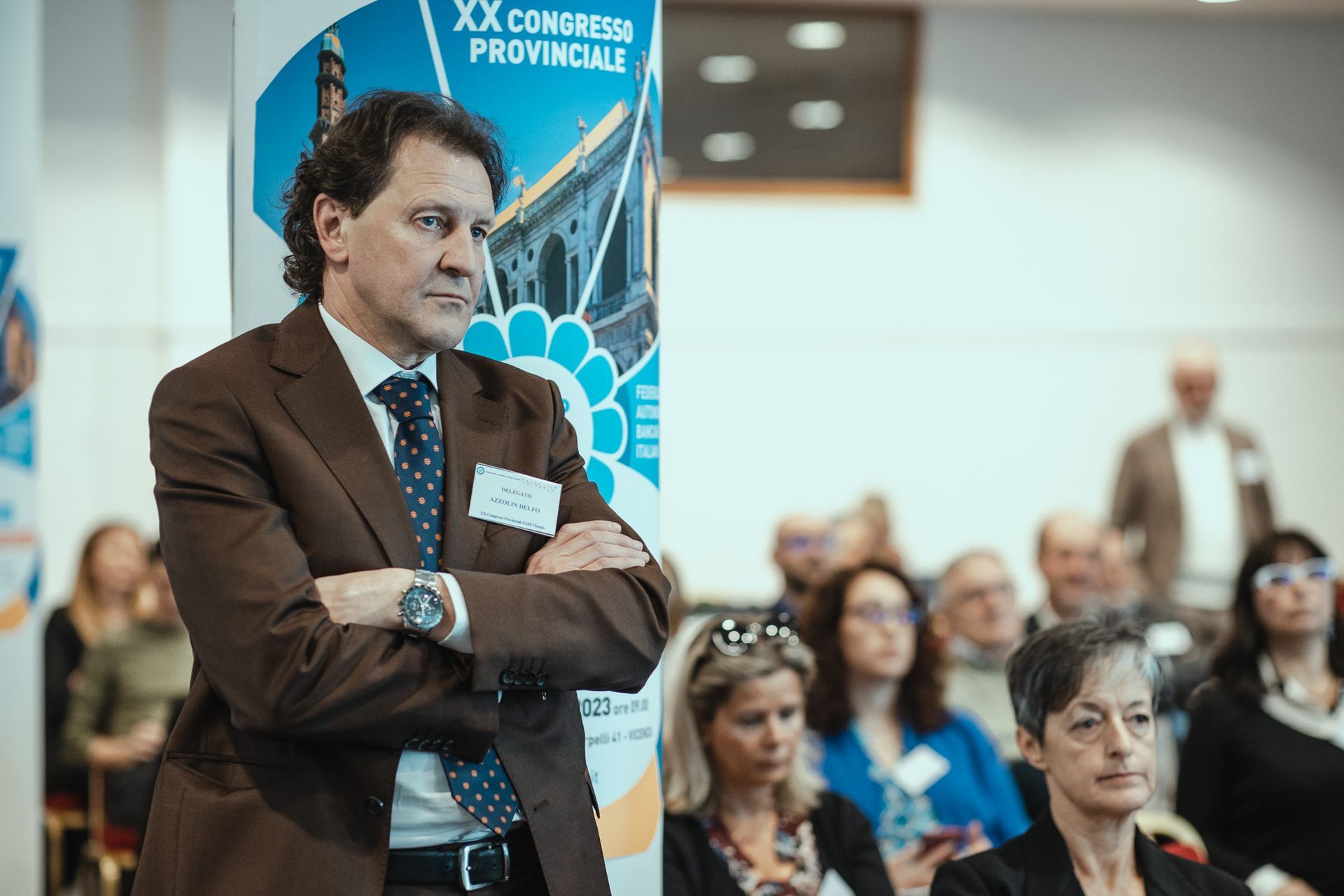 Un uomo in giacca e cravatta è in piedi di fronte a un gruppo di persone.