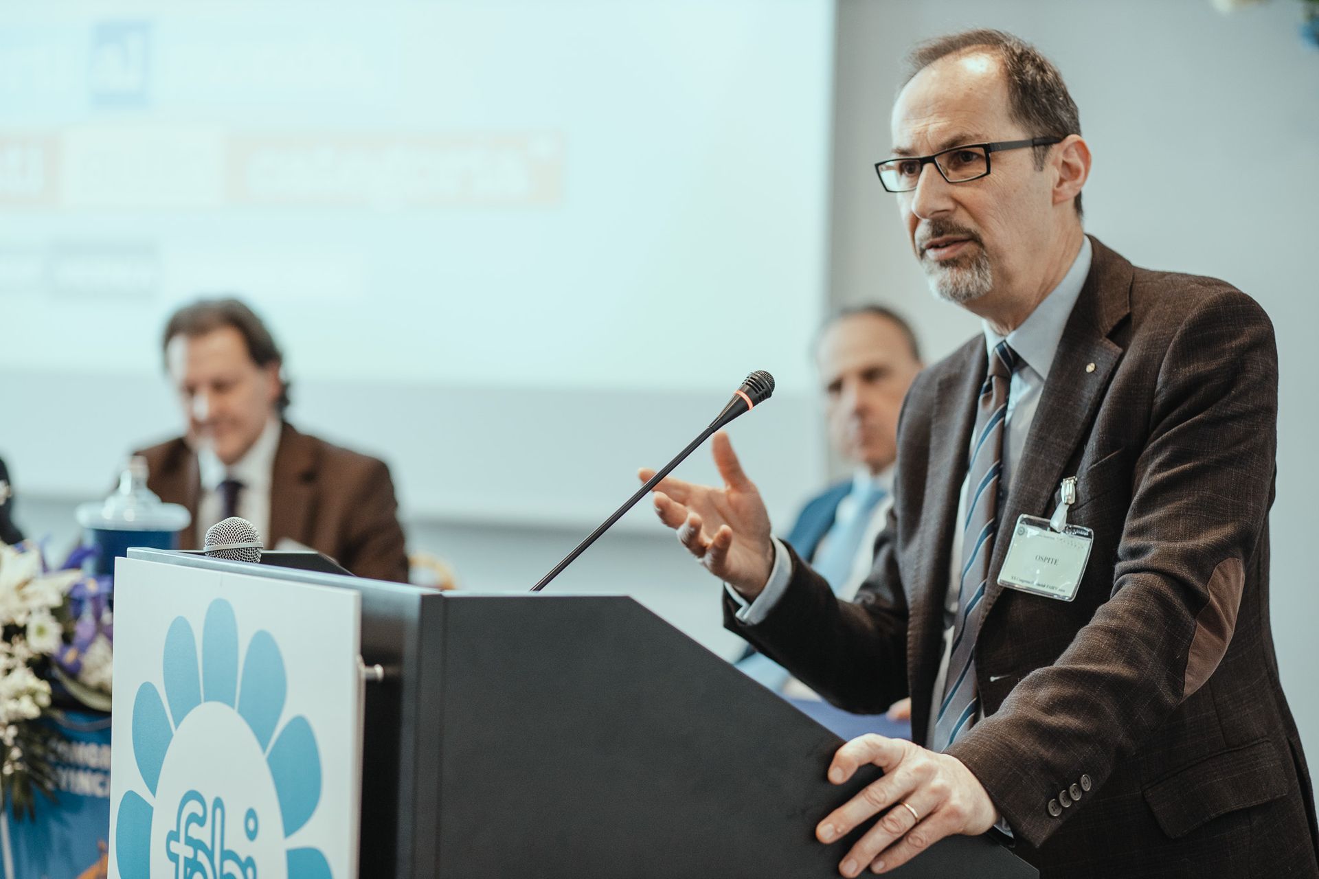 Un uomo in giacca e cravatta è in piedi su un podio e tiene un discorso.