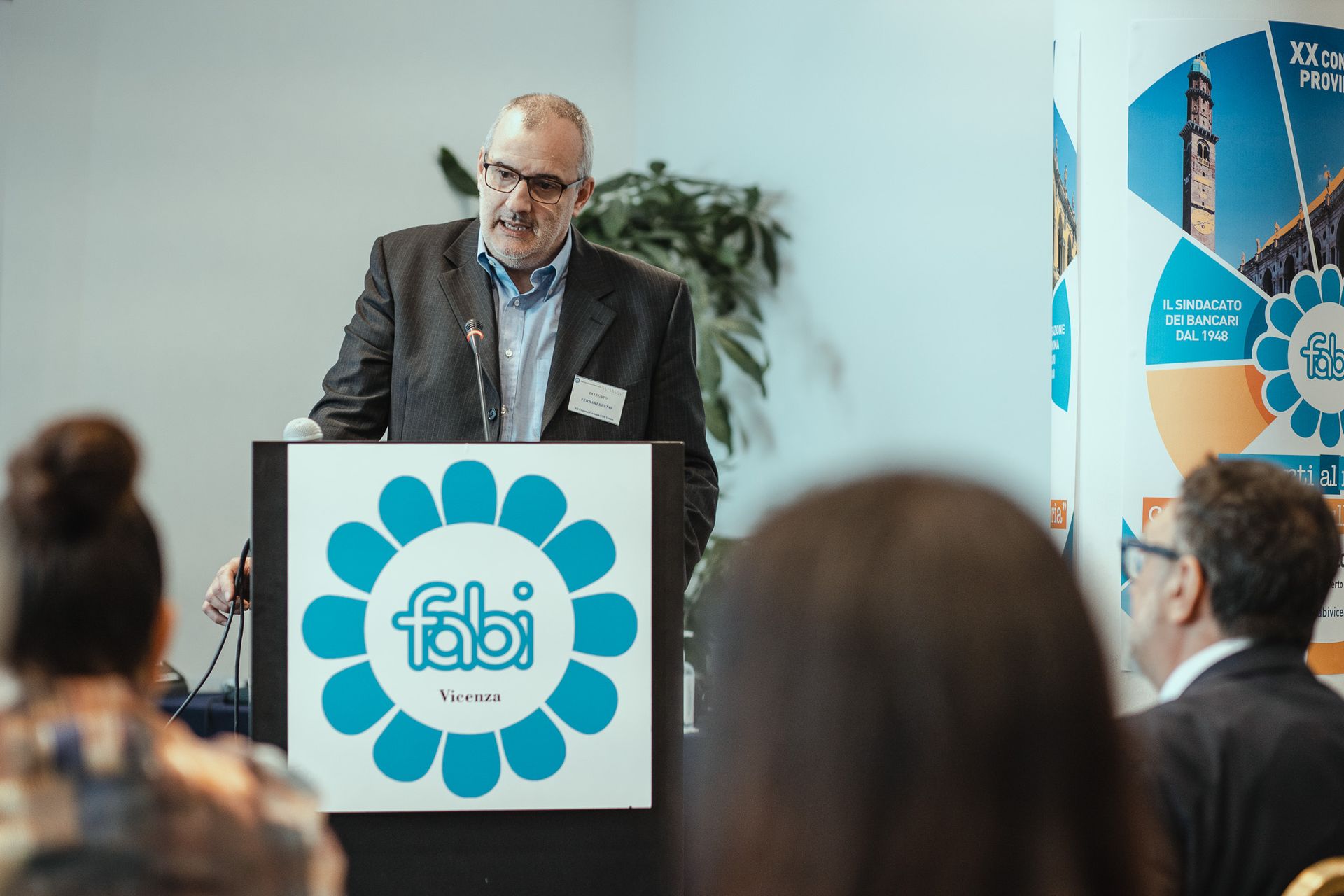 Un uomo è in piedi su un podio e tiene un discorso davanti a un gruppo di persone.