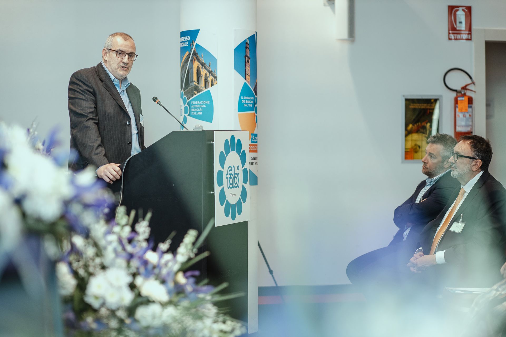 Un uomo in giacca e cravatta è in piedi su un podio e tiene un discorso.