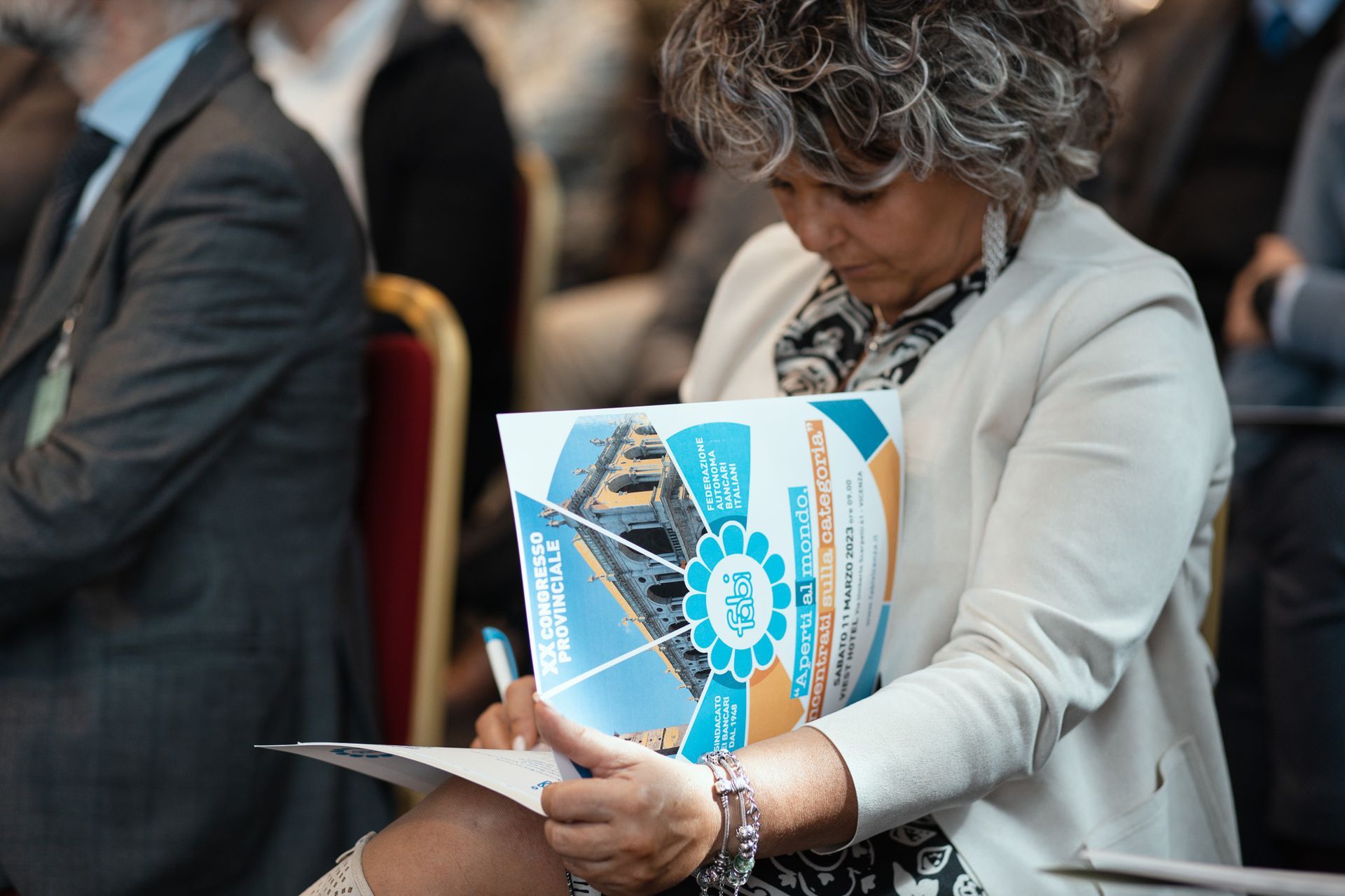 Una donna è seduta su una sedia e legge un libro.