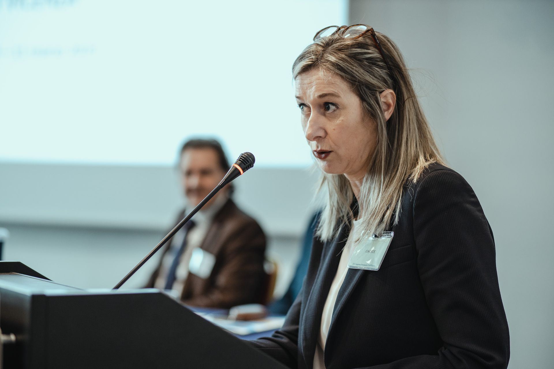 Una donna è in piedi su un podio e parla al microfono.