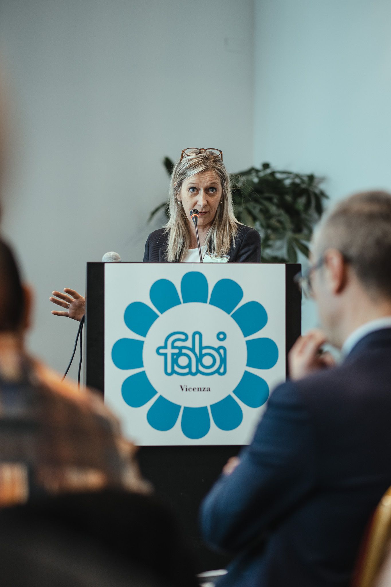 Una donna tiene un discorso su un podio con sopra un favoloso logo.