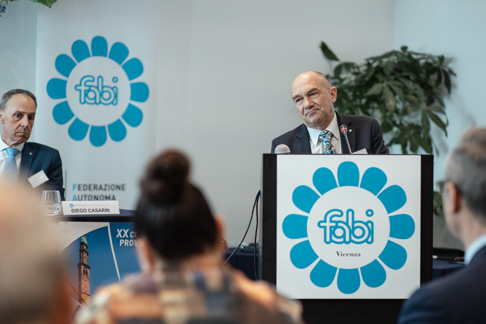 Un uomo è in piedi su un podio e tiene un discorso davanti a un gruppo di persone.