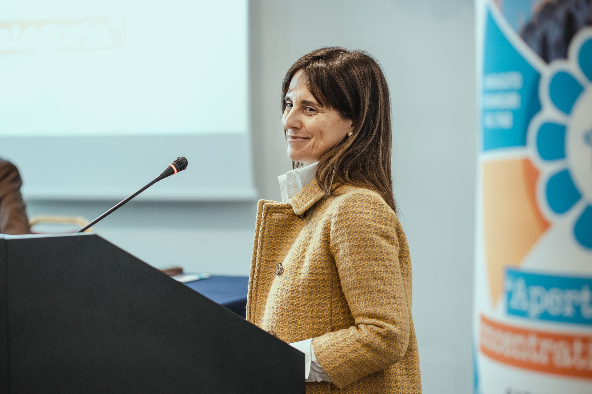 Una donna è in piedi su un podio con un microfono davanti a sé.