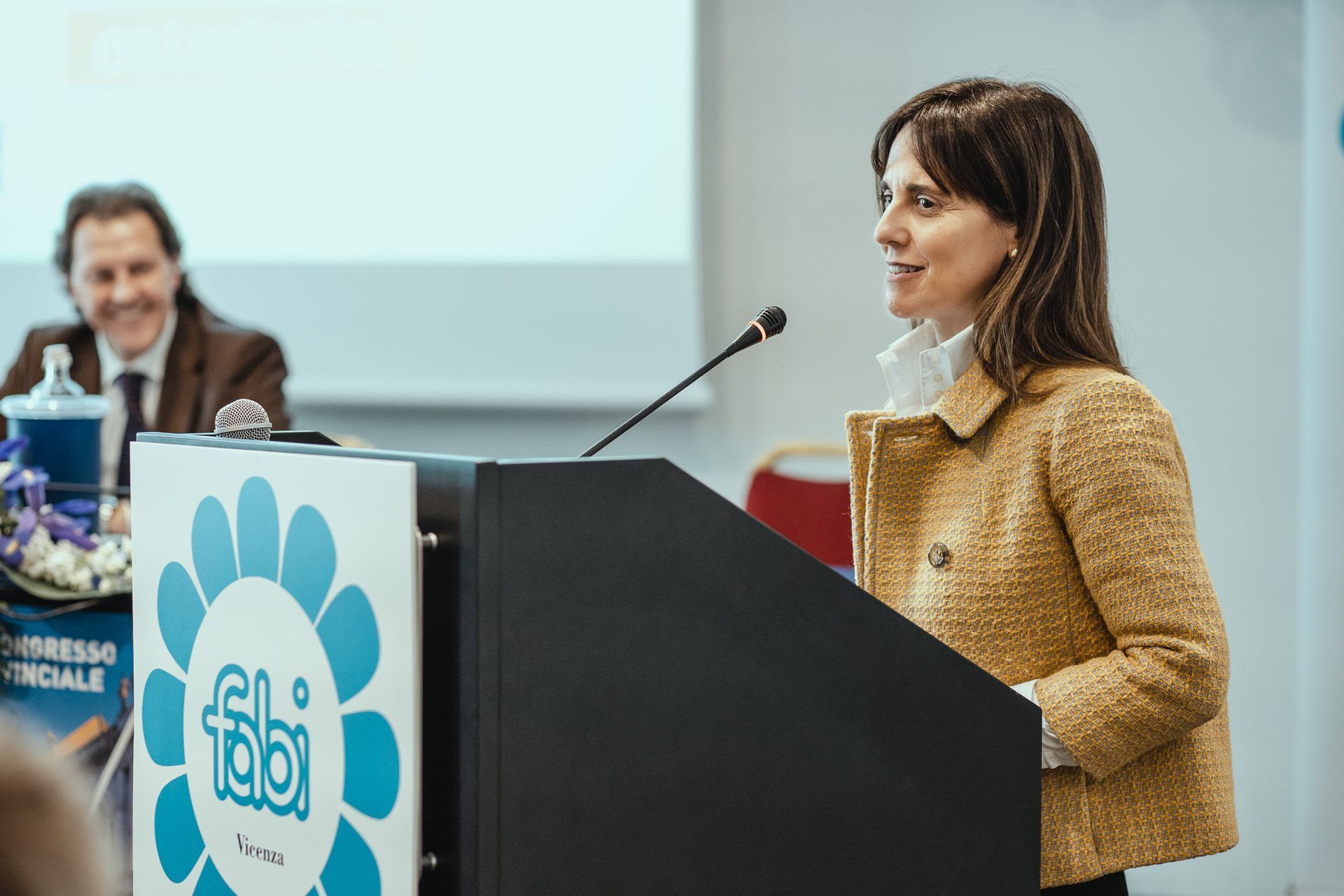 Una donna è in piedi su un podio e parla al microfono.