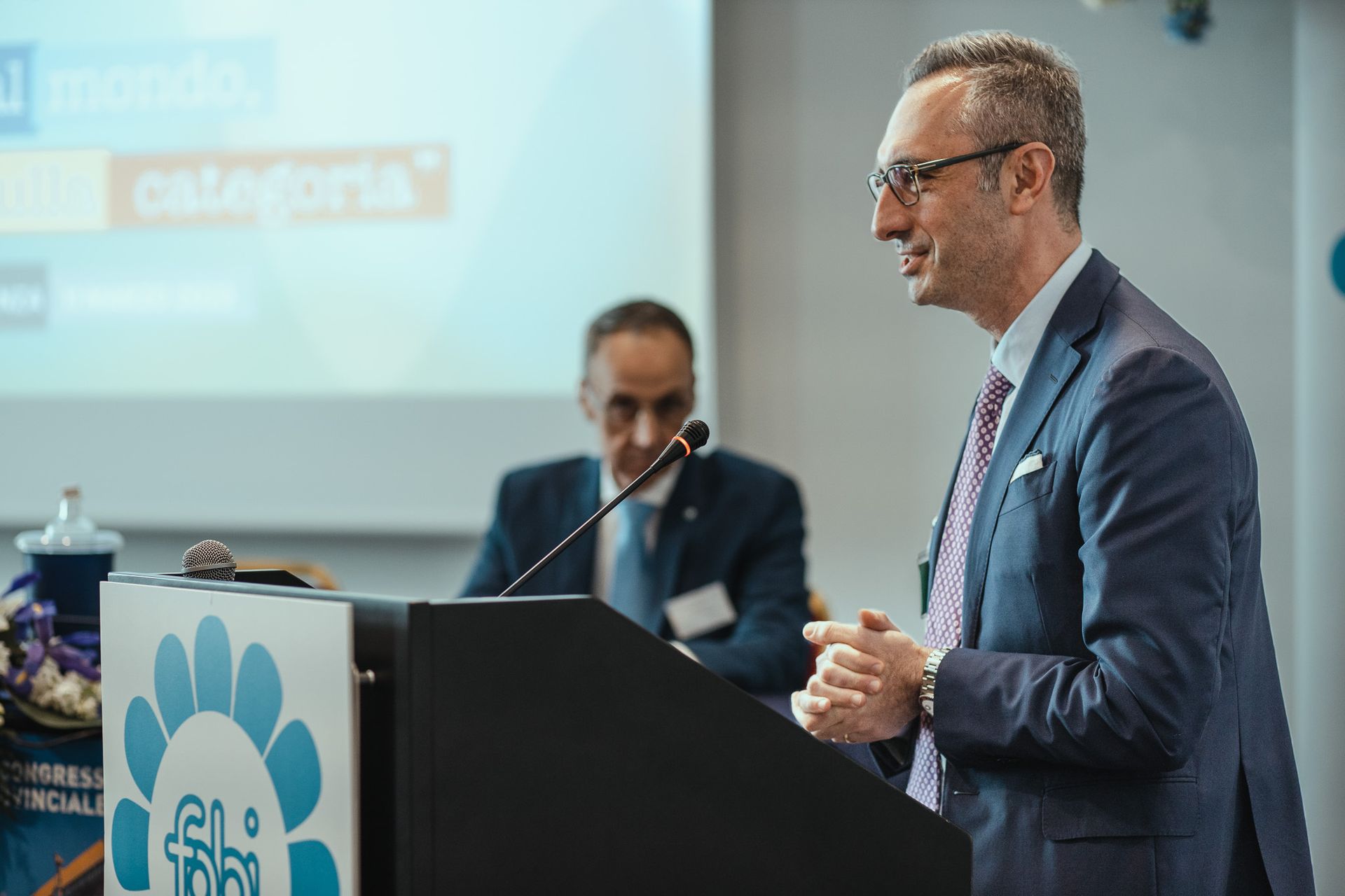 Un uomo in giacca e cravatta è in piedi su un podio e tiene un discorso.