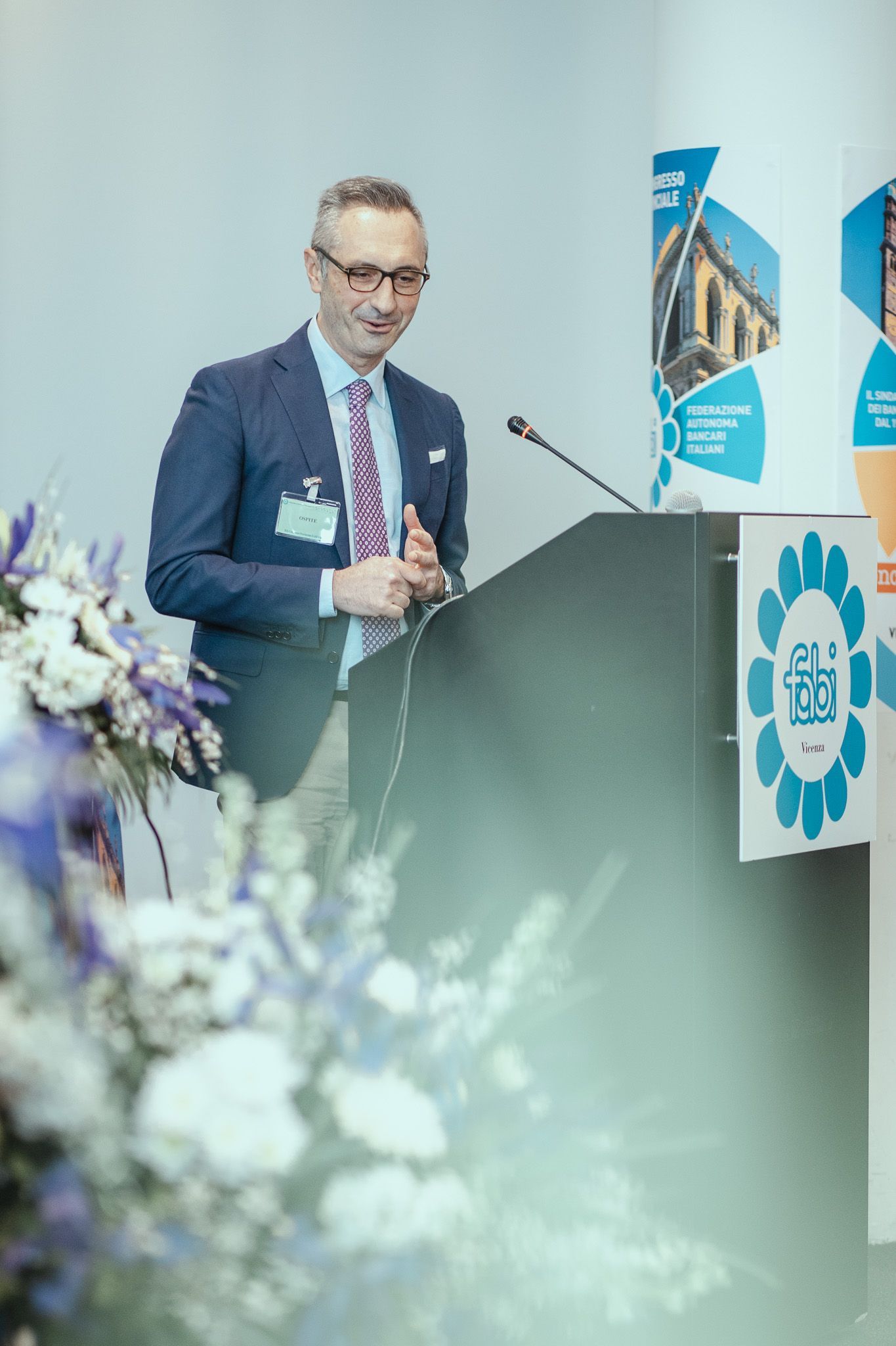 Un uomo in giacca e cravatta è in piedi su un podio e tiene un discorso.