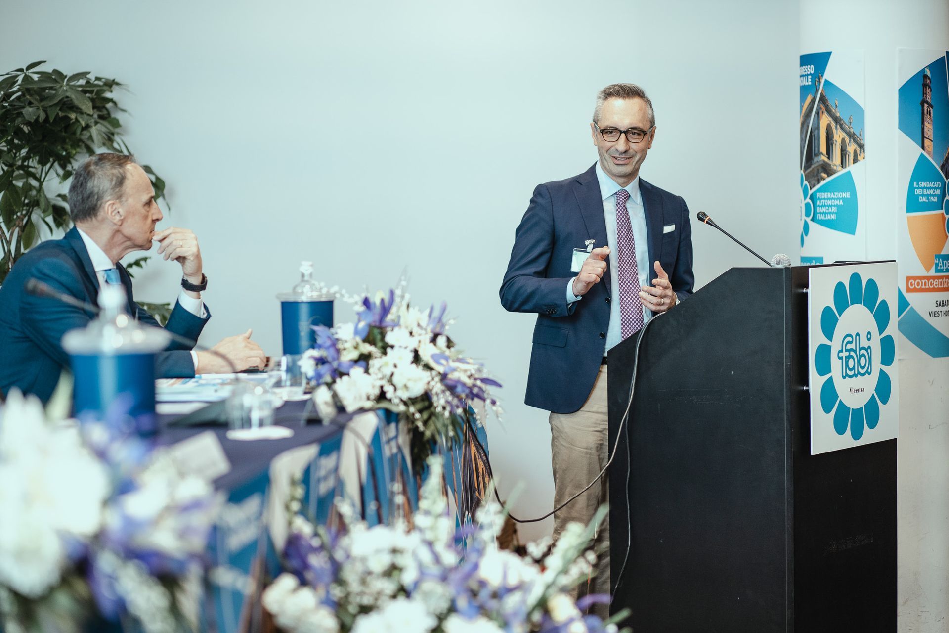 Un uomo in giacca e cravatta è in piedi su un podio mentre fa una presentazione.