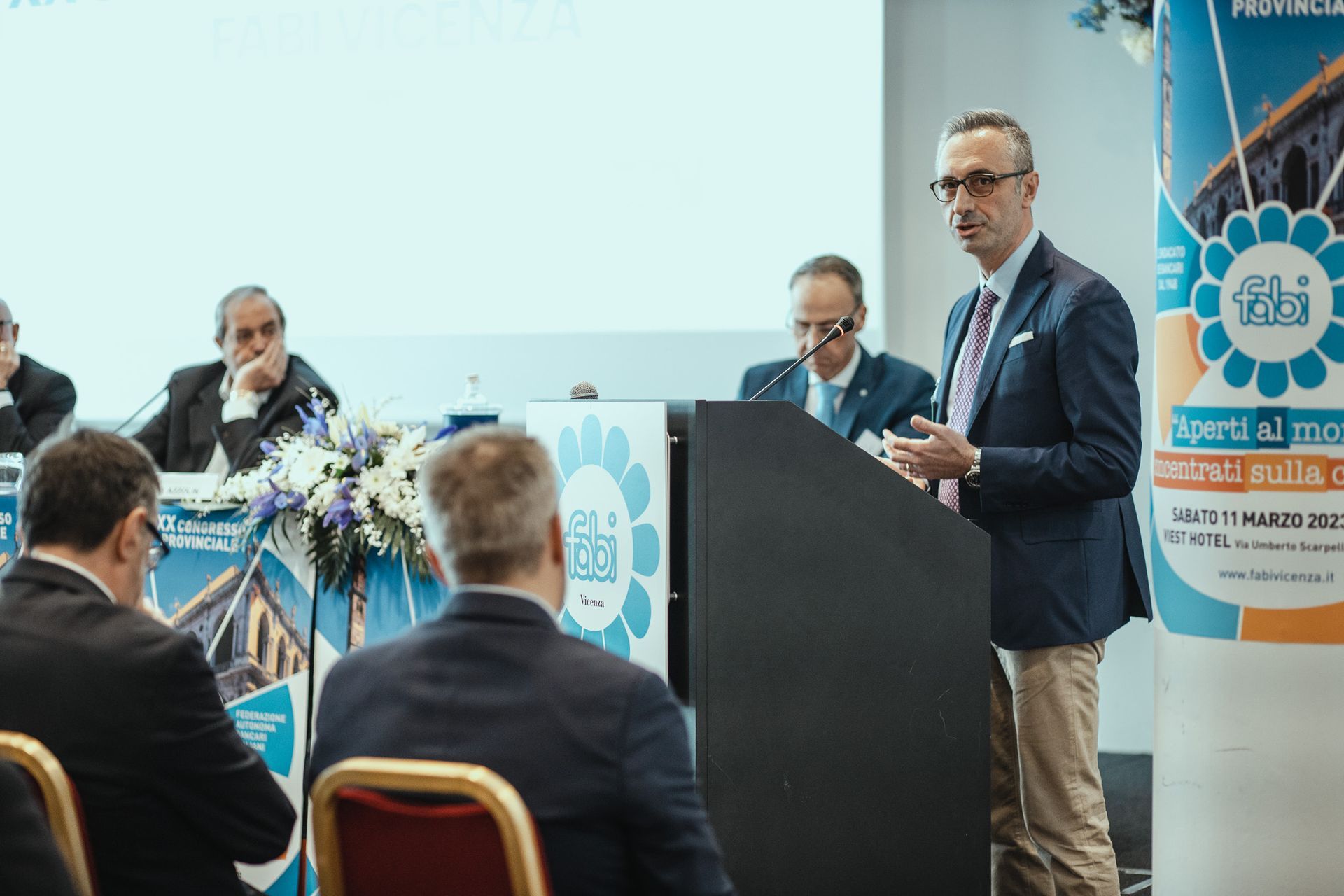 Un uomo è in piedi su un podio e fa una presentazione a un gruppo di persone.