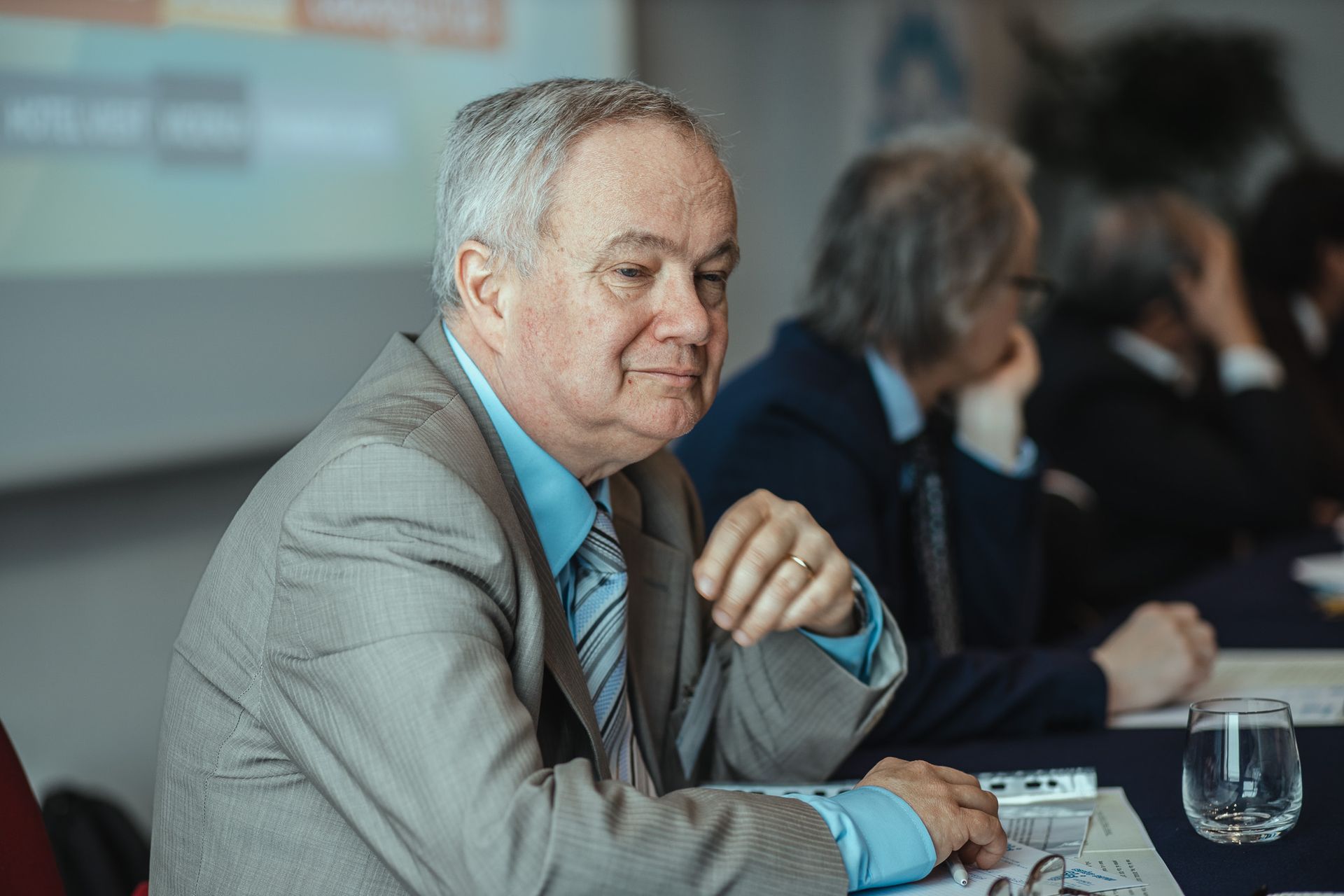 Un uomo in giacca e cravatta è seduto a un tavolo.