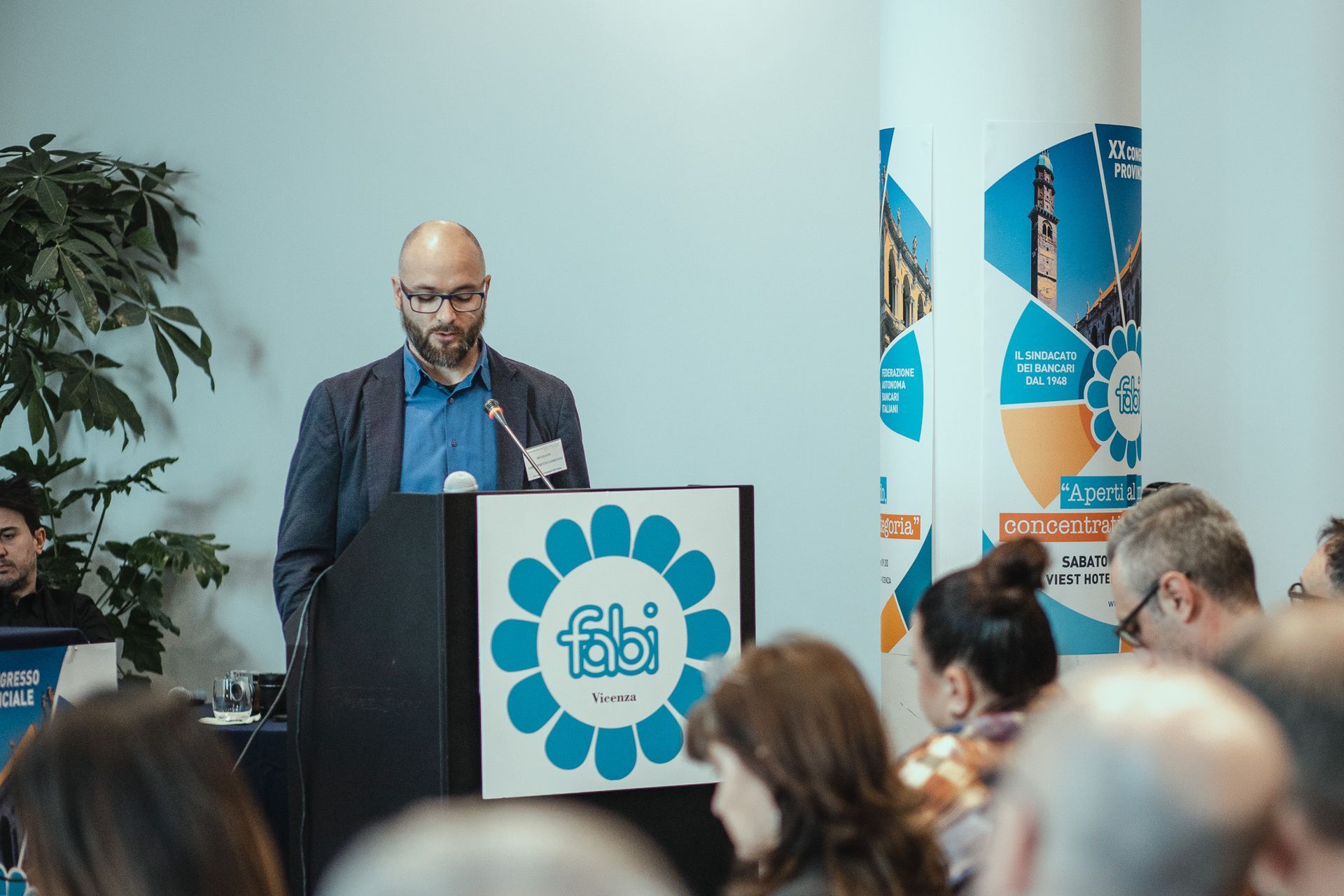 Un uomo è in piedi su un podio e fa una presentazione a un gruppo di persone.