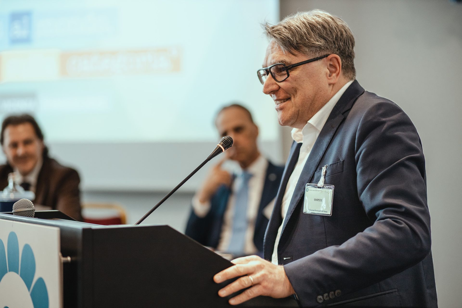 Un uomo in giacca e cravatta è in piedi su un podio e tiene un discorso.